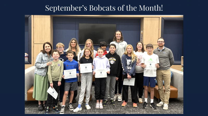 Group of students and adults posing indoors, several holding certificates, under a Bobcat of the Month banner.