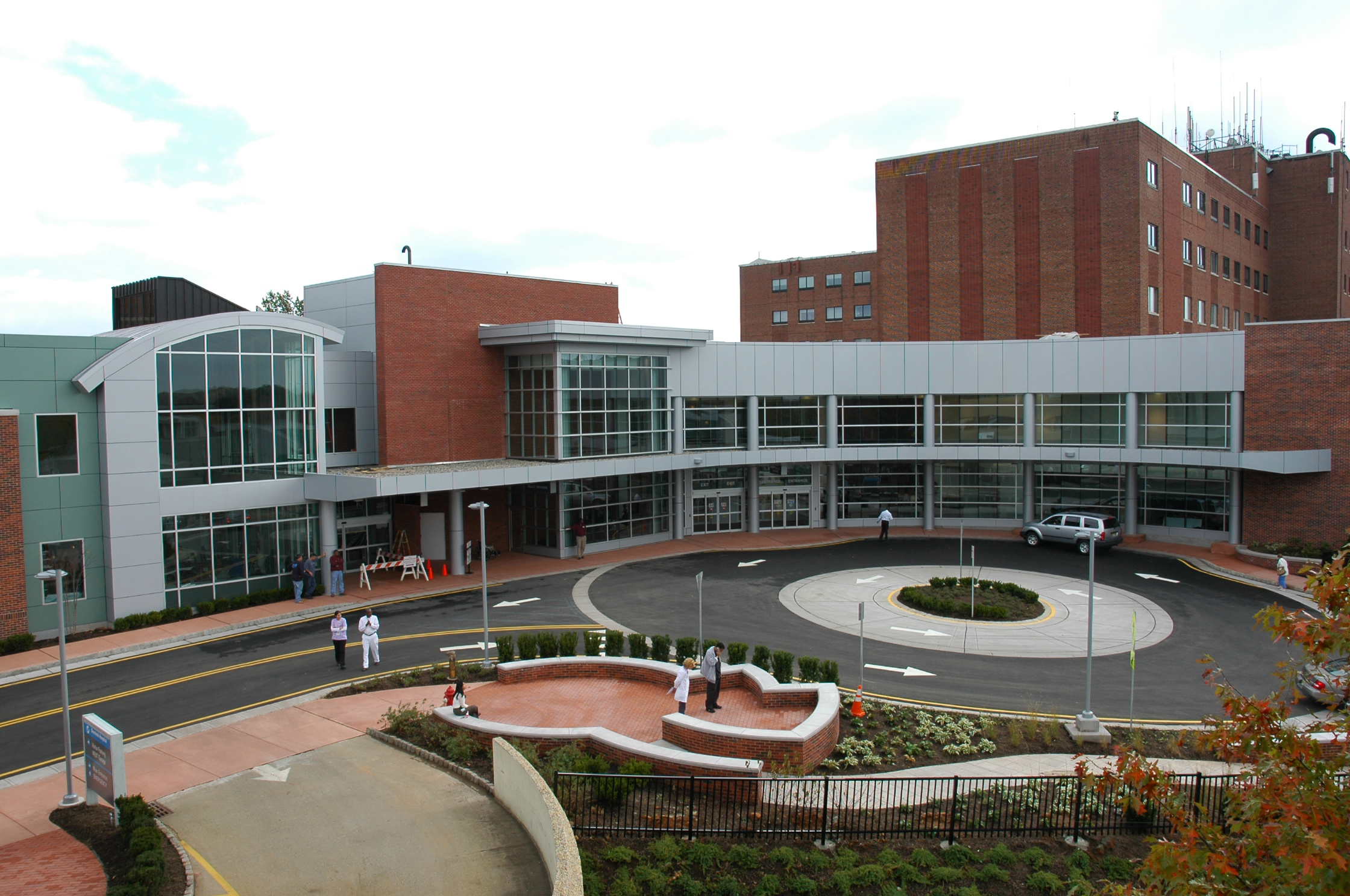 Aerial exterior view of a large brick hospital complex with a glass entrance and circular driveway.