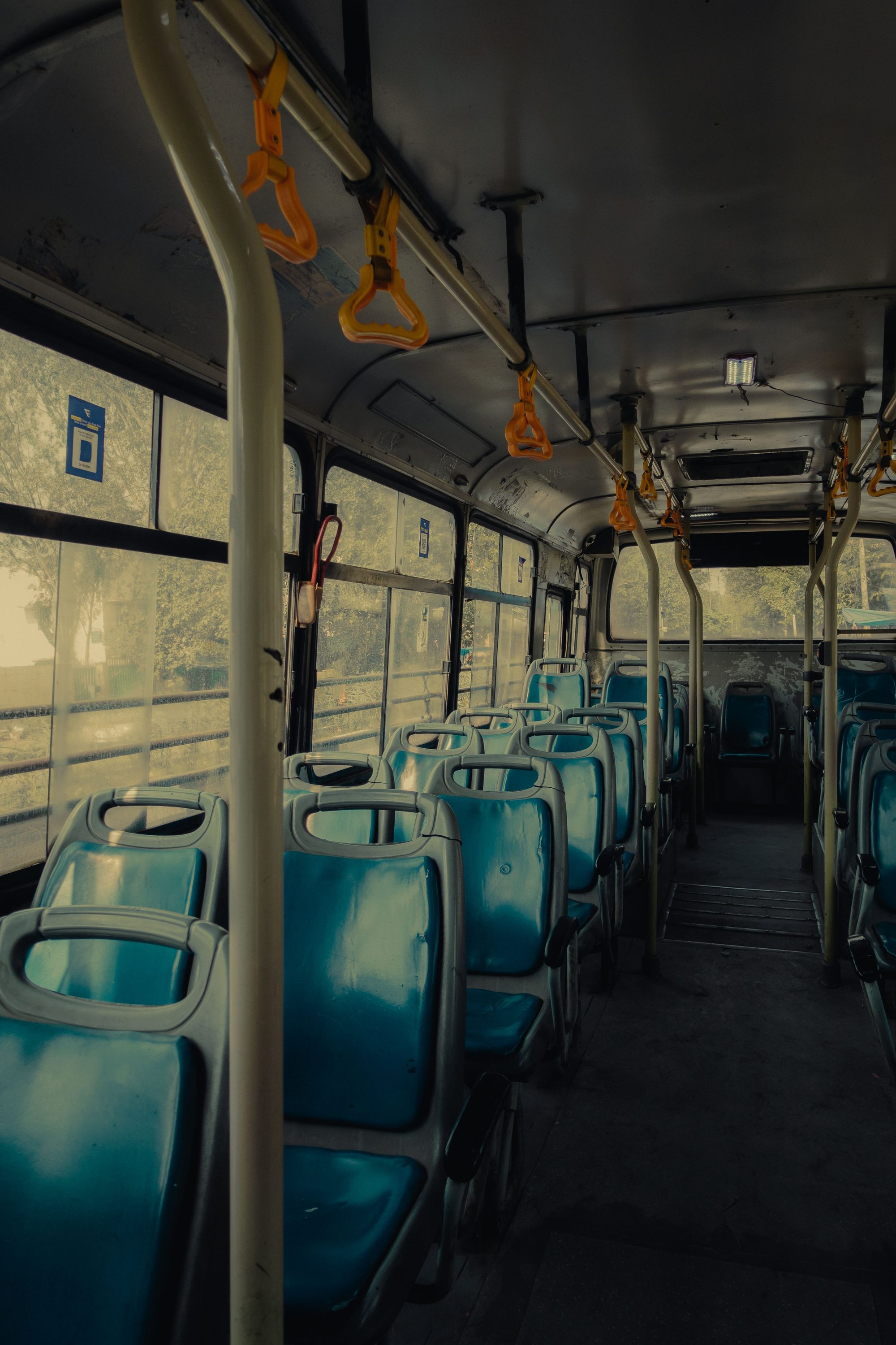 A quiet and empty interior of a public bus with blue seats and yellow handrails, offering urban transport atmosphere.