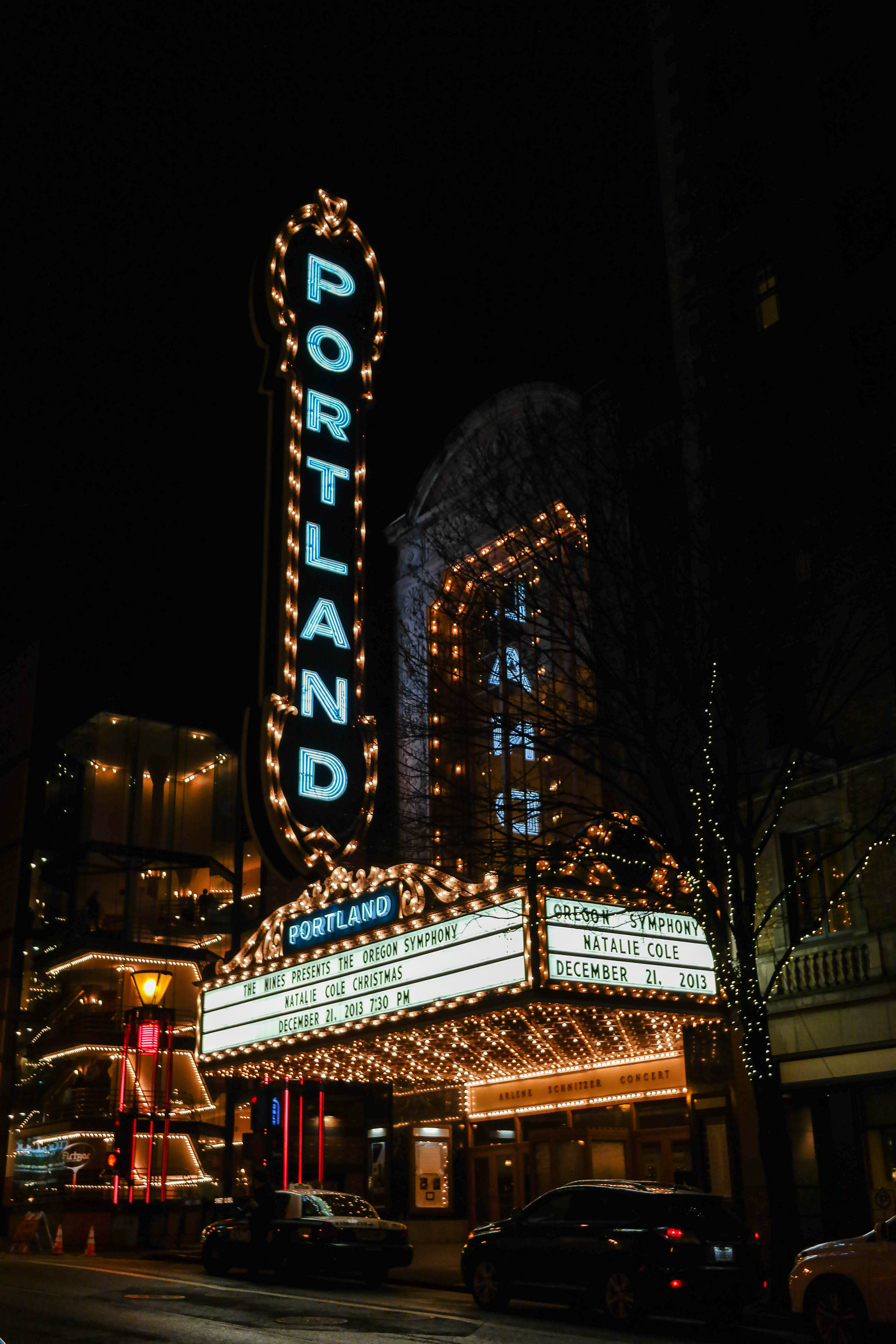 Illuminated vertical neon Portland sign on a concert hall facade at night.
