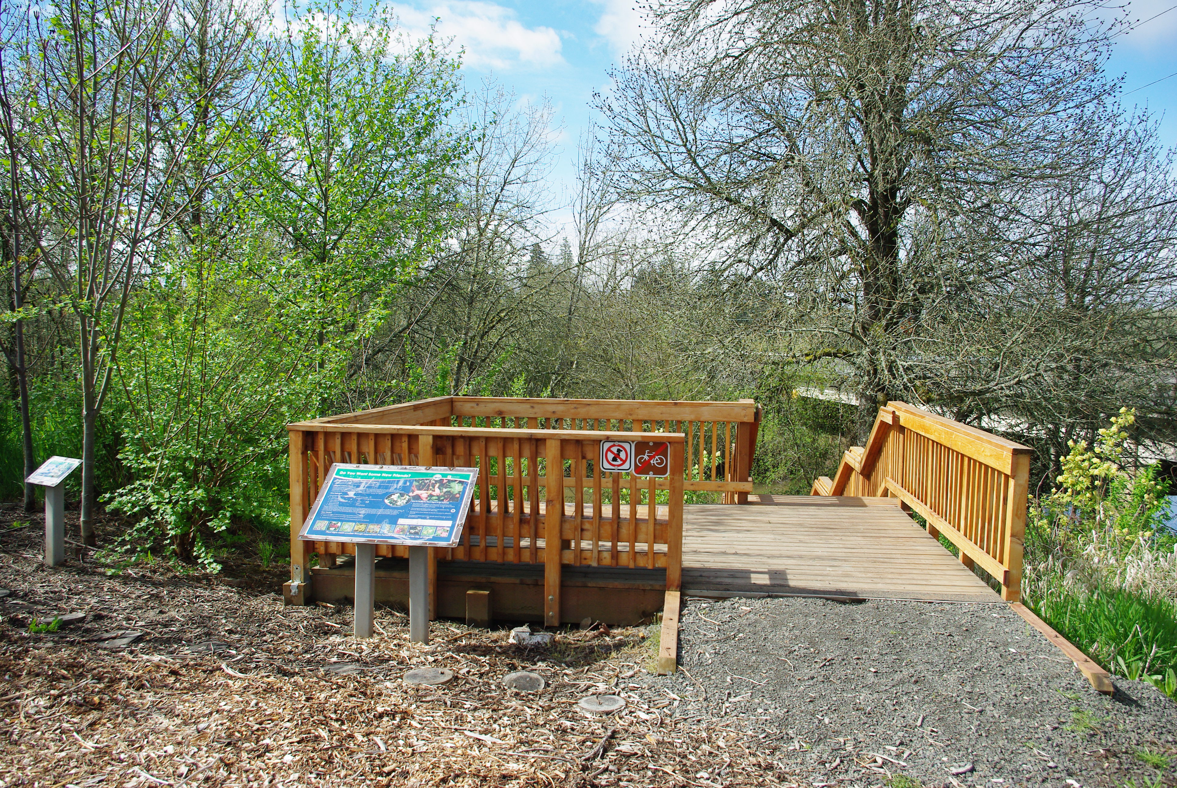 Wooden overlook platform with railing and interpretive sign at a wetlands preserve.