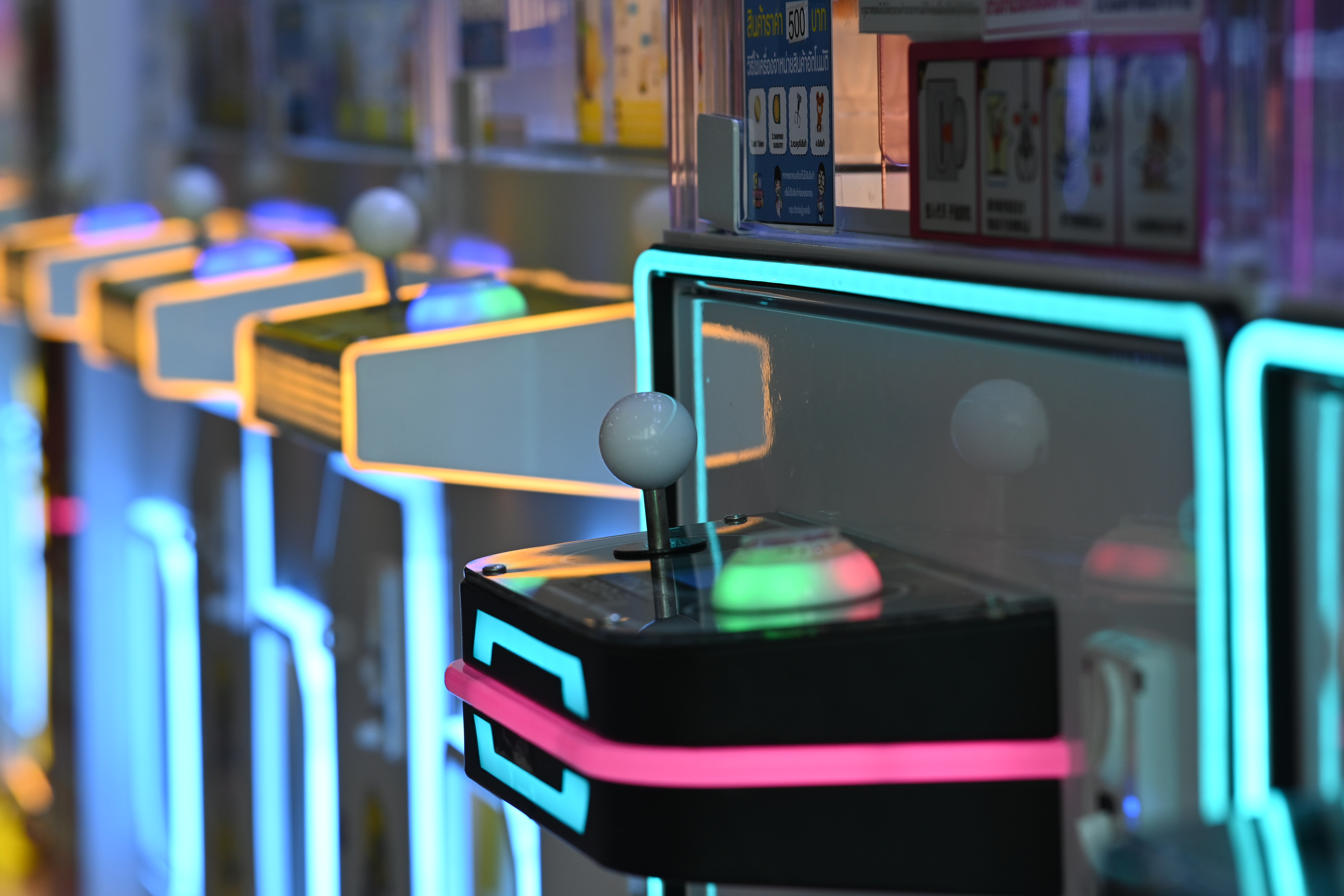 Close-up of retro arcade joysticks glowing with neon blue and pink lights.