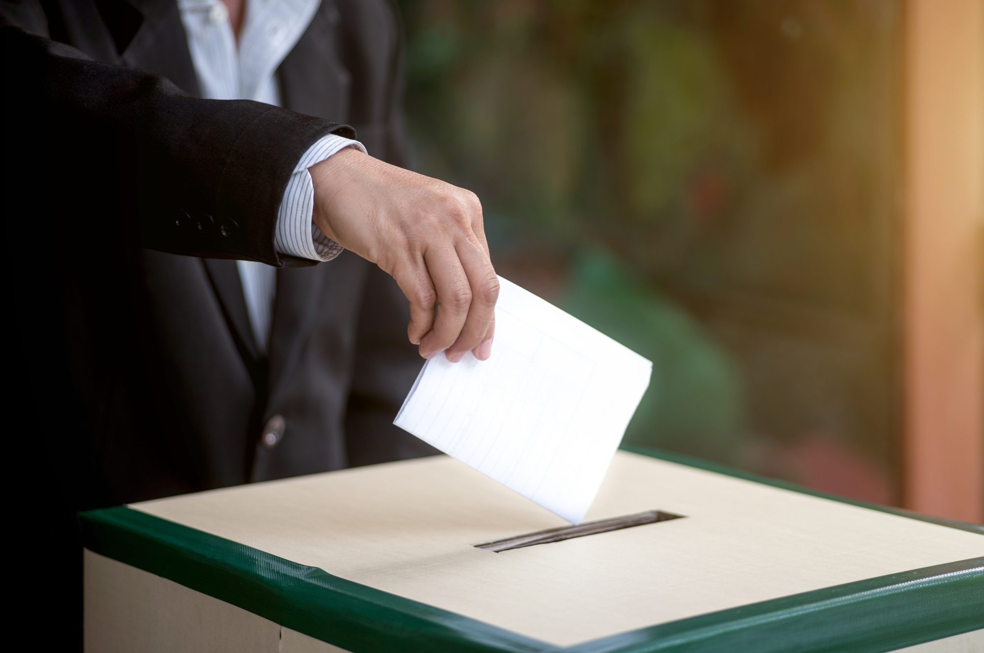 Hand of a person casting a vote into the ballot box during elections.