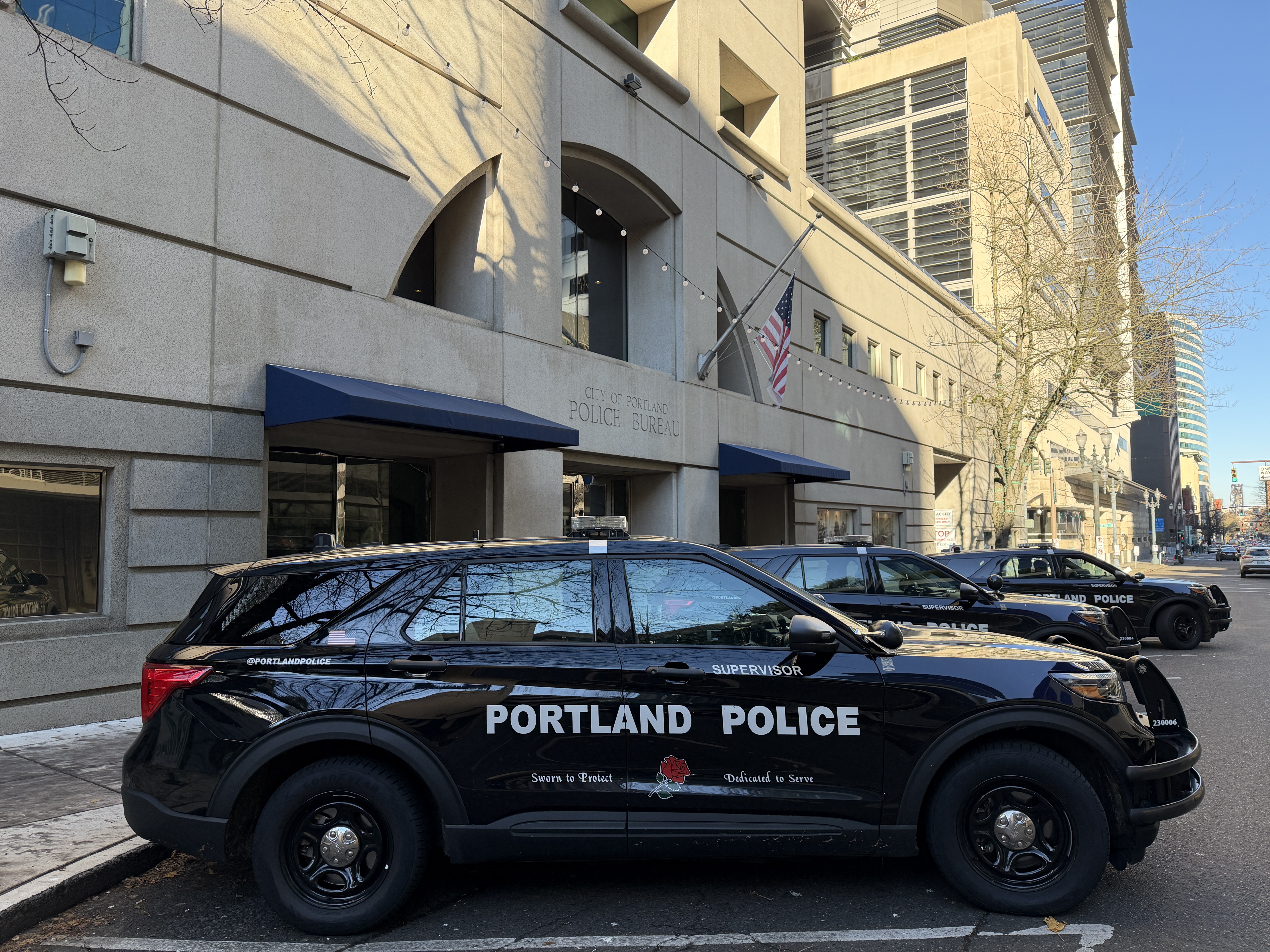 Exterior of the Portland Police Bureau headquarters with a marked police SUV parked outside.
