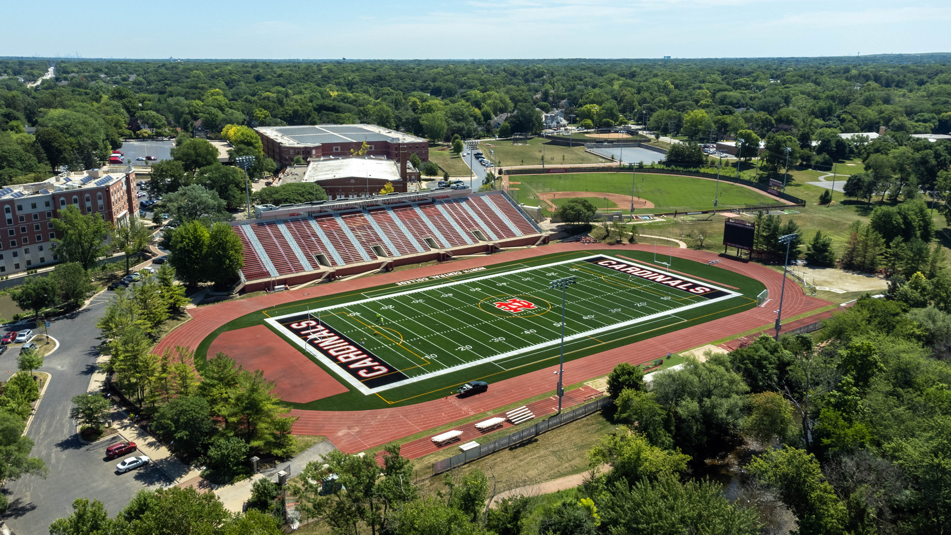 Aerial view of a football stadium with red running track and Cardinals end zone lettering.