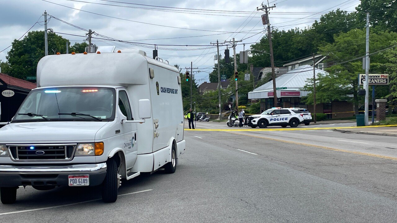 Police vehicles and crime scene tape block a road at a commercial intersection.