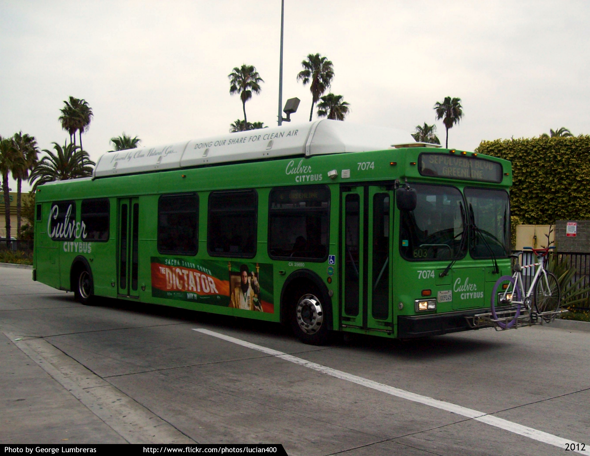 Green Culver CityBus with a bicycle rack mounted on the front, stopped on a street.