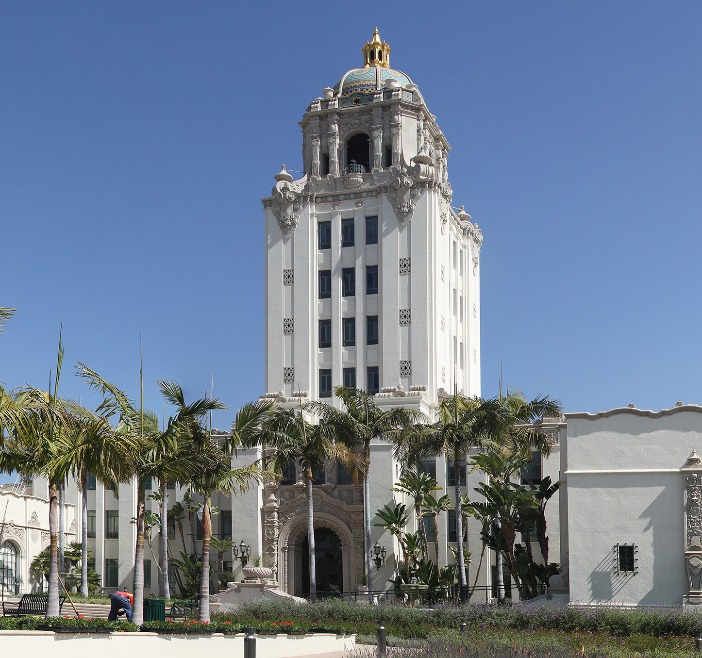 White Spanish Colonial Revival tower of Beverly Hills City Hall framed by palm trees.