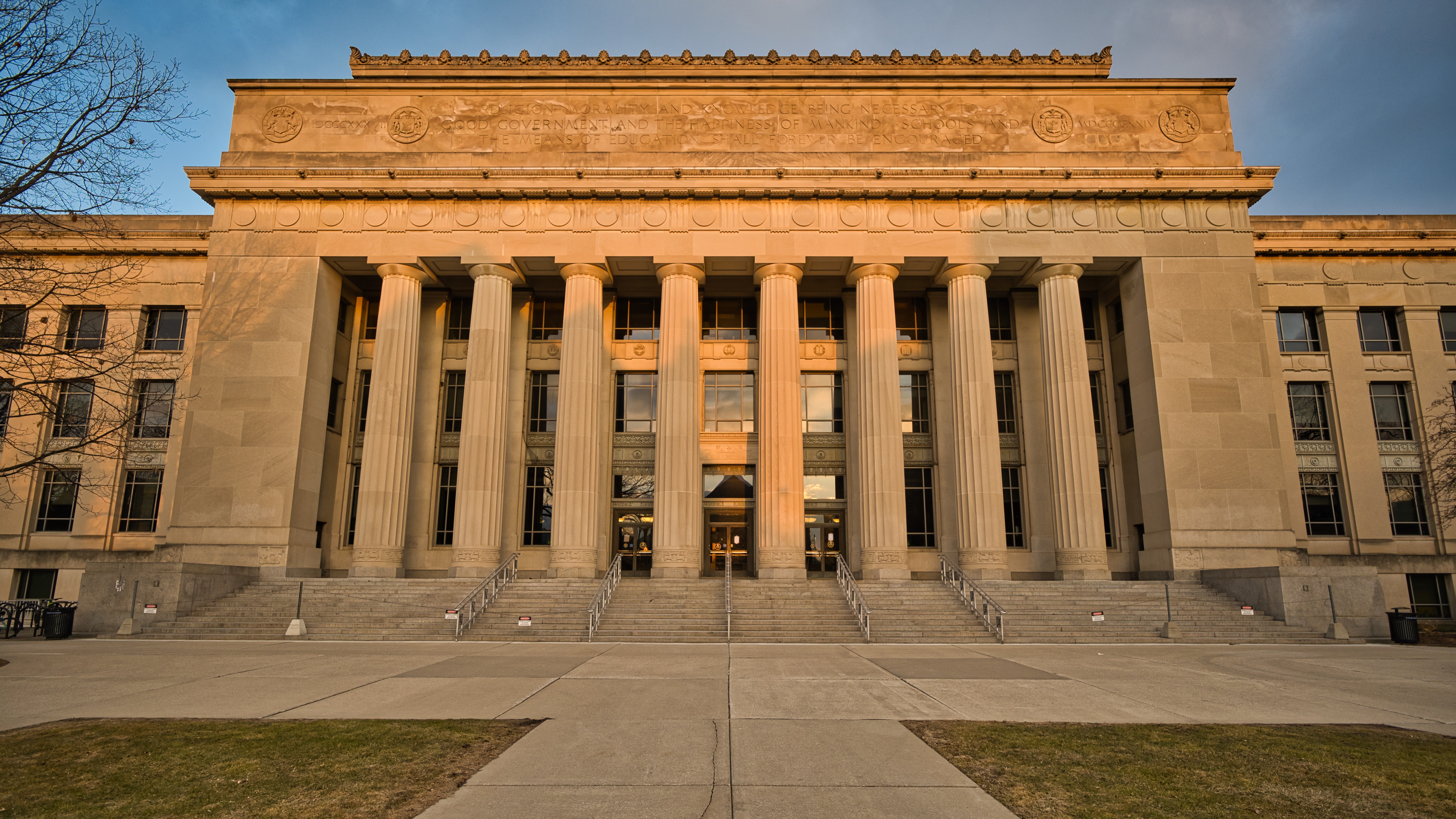 Neoclassical stone building with tall columns and wide steps bathed in warm golden-hour light.