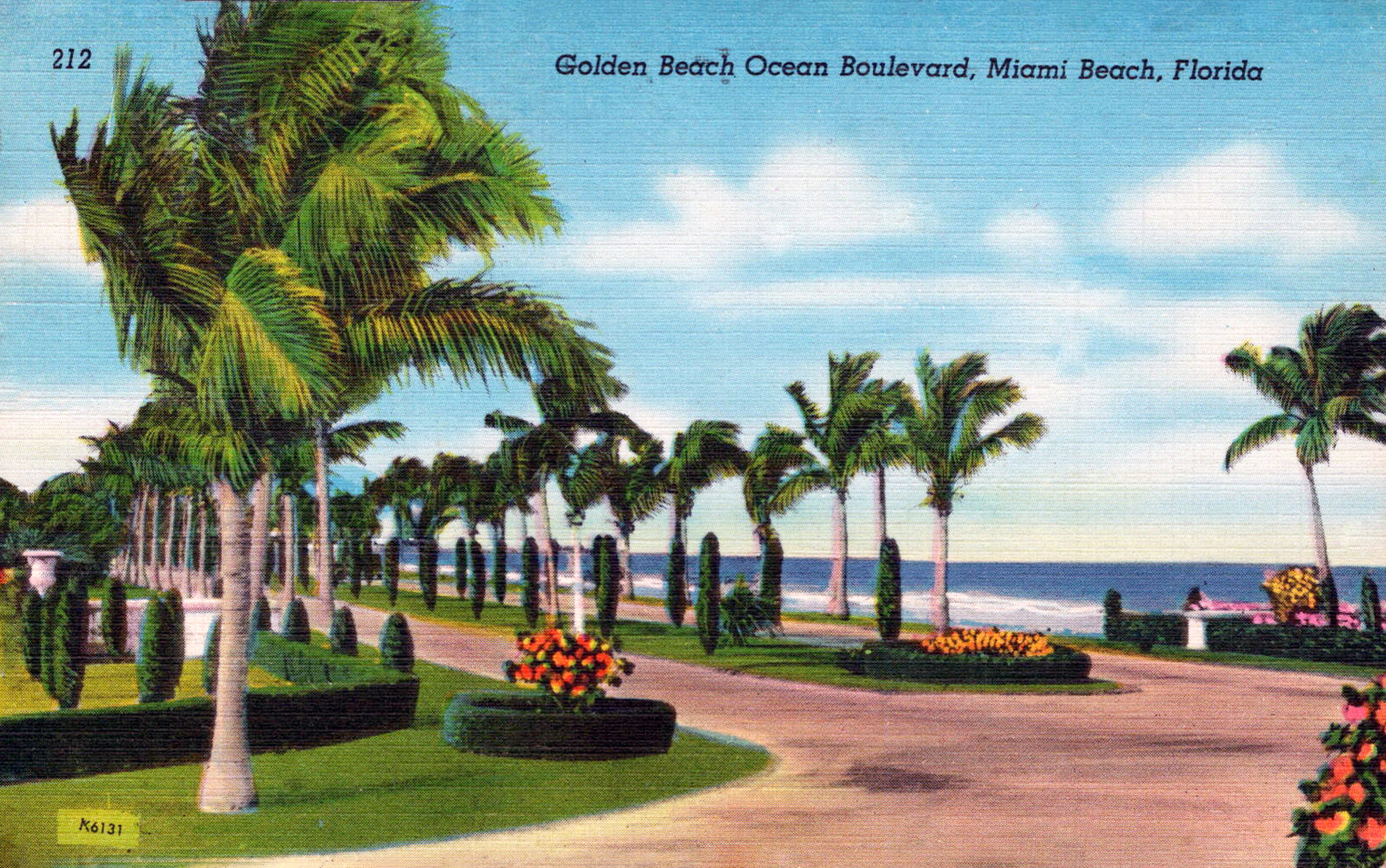 Vintage tinted postcard of a palm-tree-lined boulevard with tropical landscaping and ocean view.
