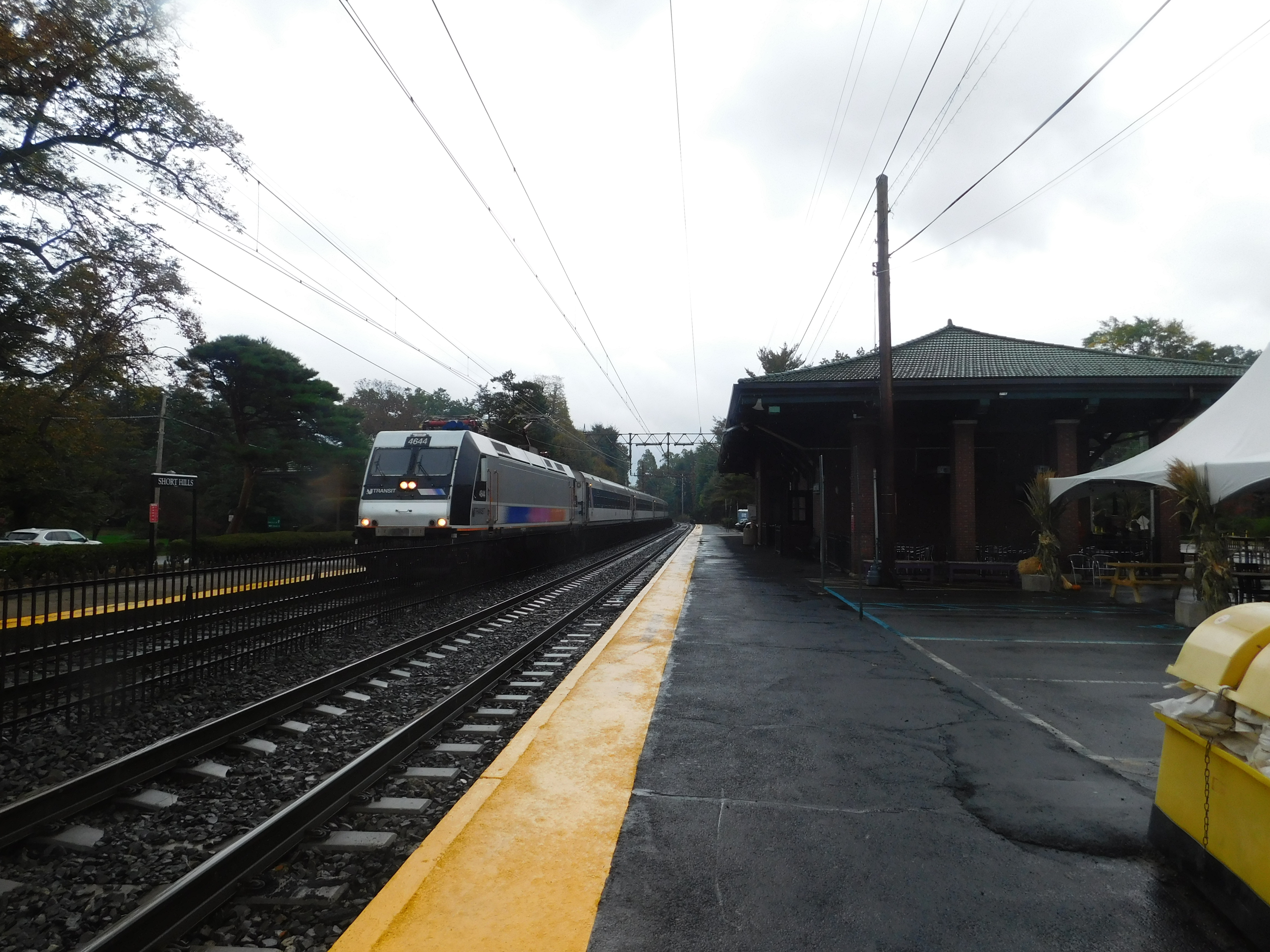 Train station platform and building with overhead wires on a sunny day.