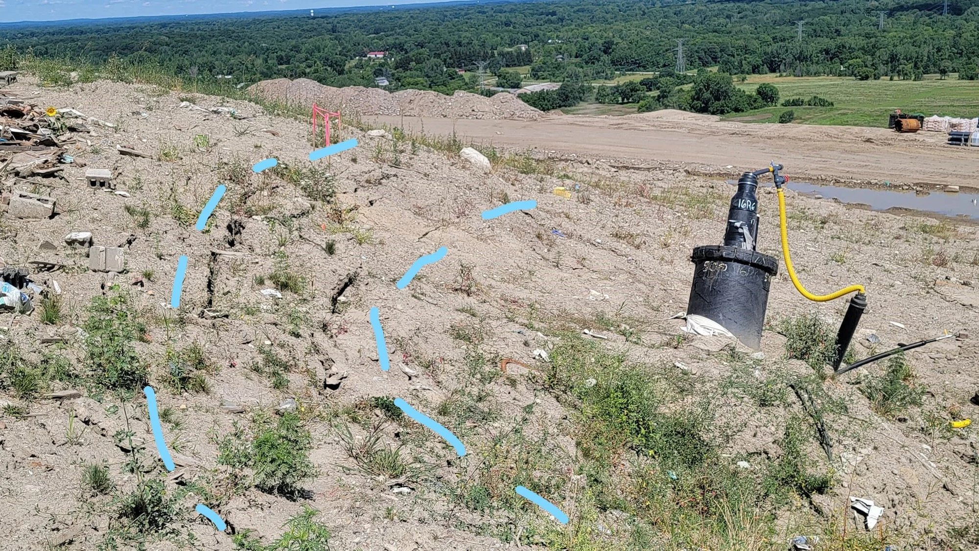 Cracked, barren earthen slope with annotated arrows pointing to soil fissures.