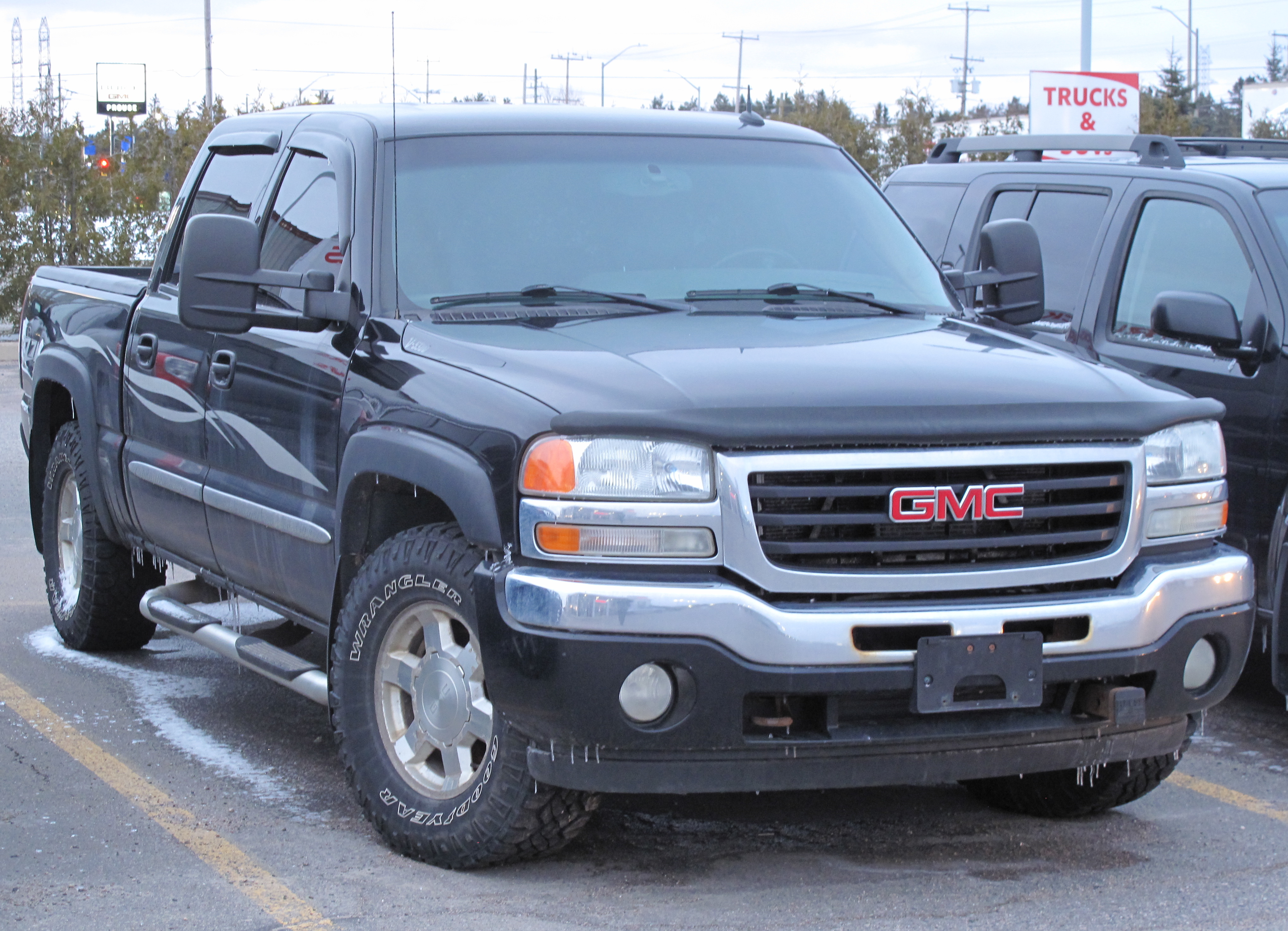 Black GMC Sierra pickup truck parked in a lot, front three-quarter view.