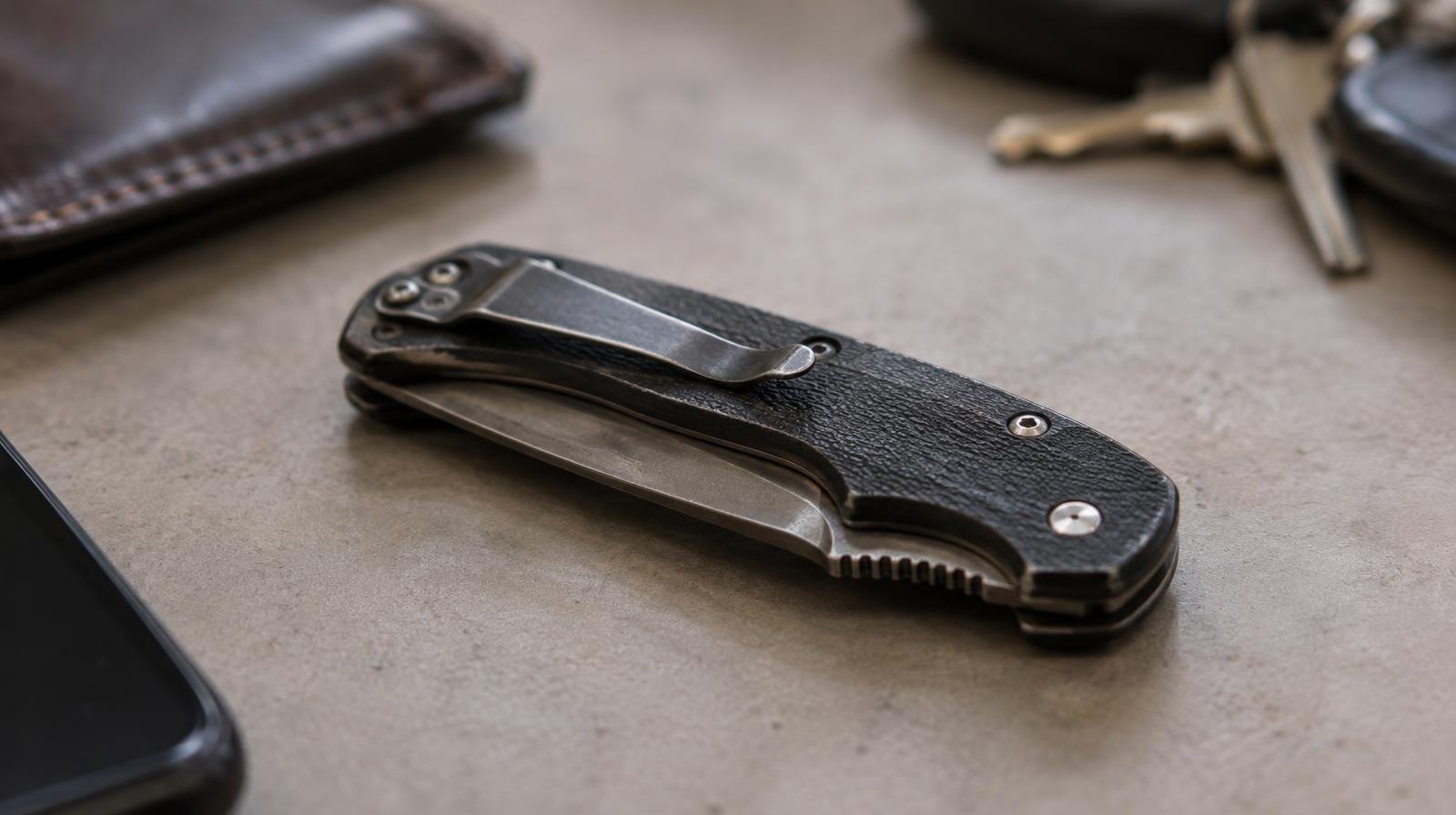 A closed folding knife resting on a neutral surface.