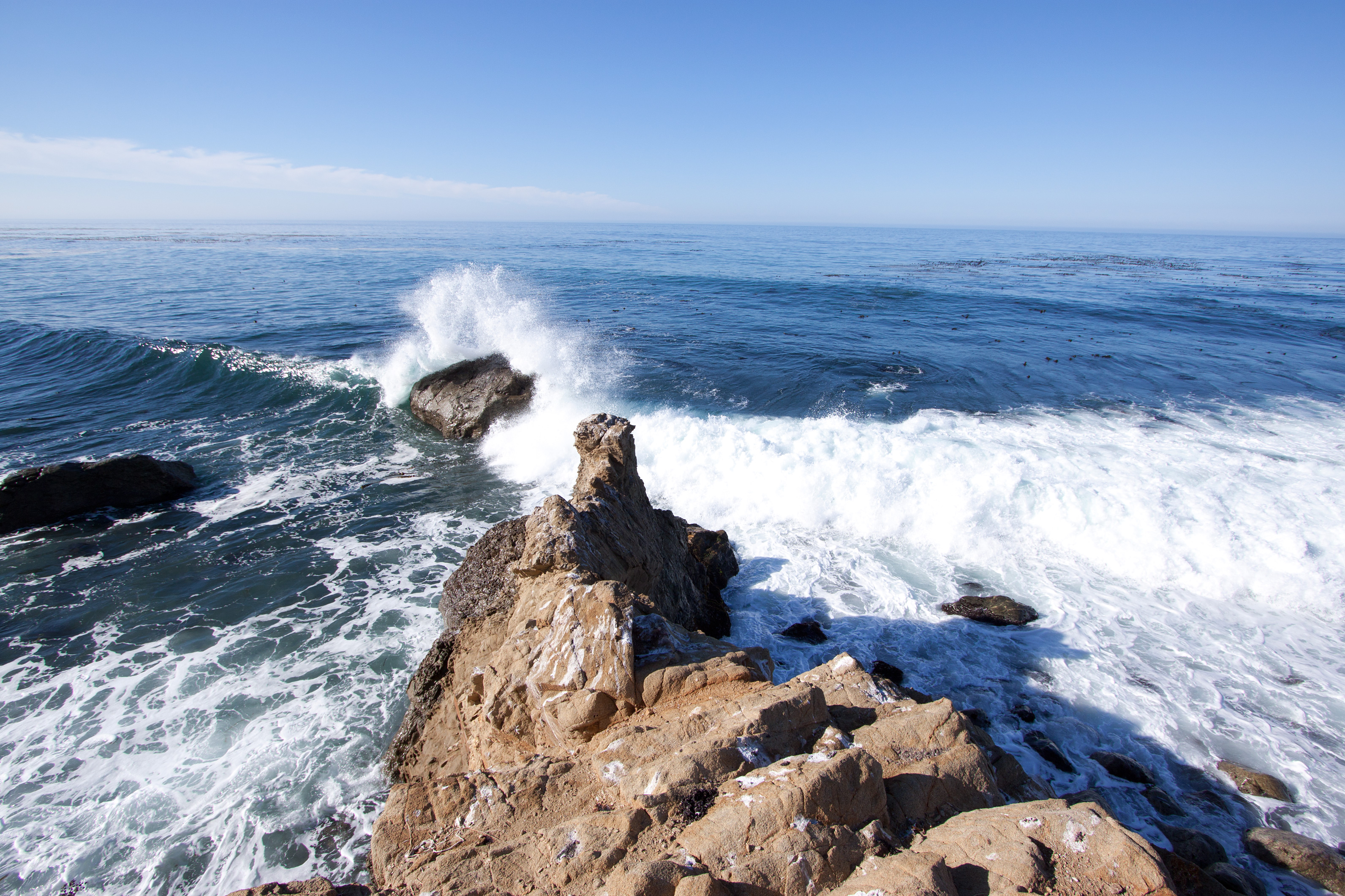 Ocean waves crashing against rocky coastal outcroppings with white sea foam.