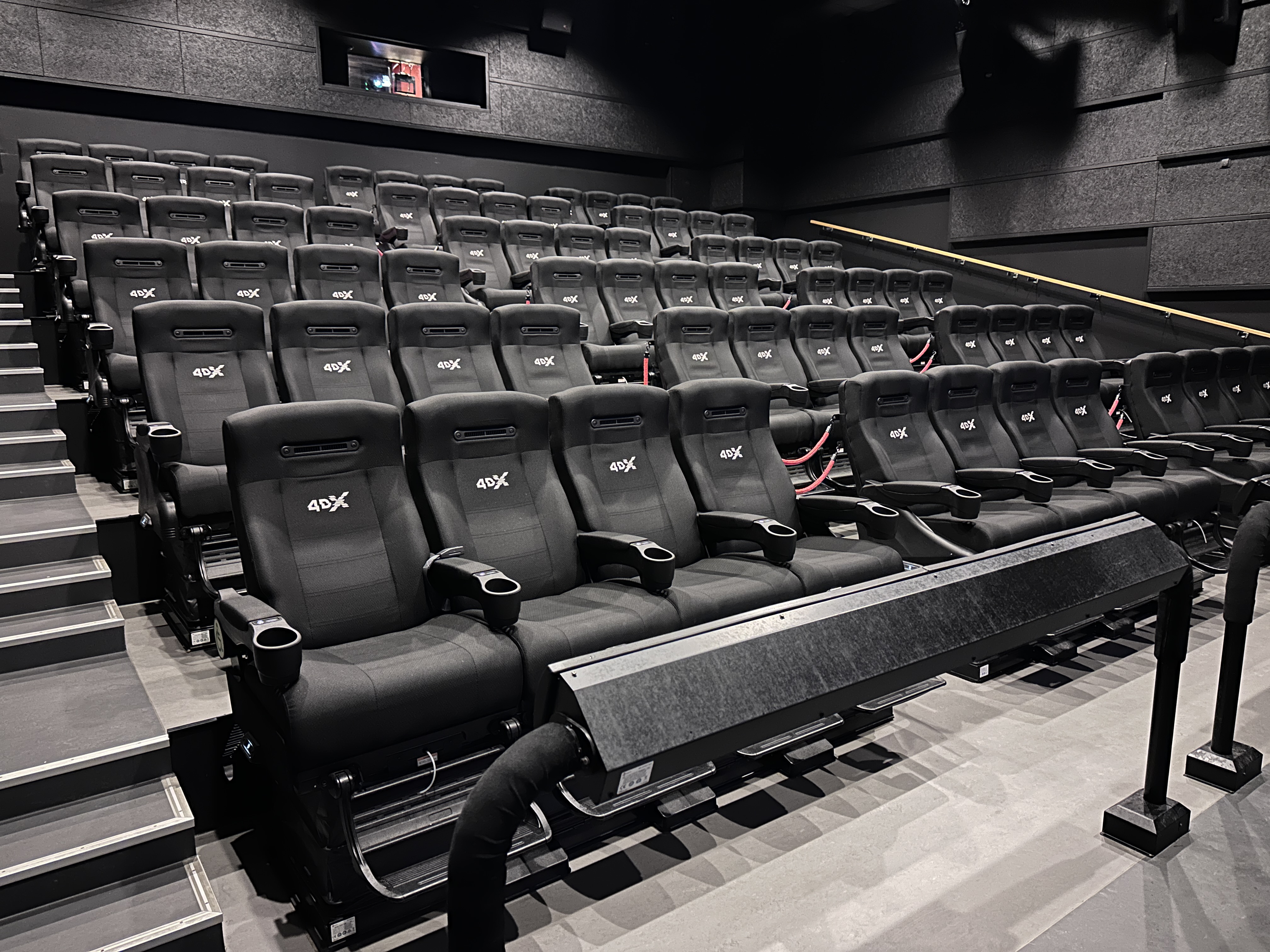 Tiered rows of black 4DX-branded motion seats in a darkened cinema auditorium.