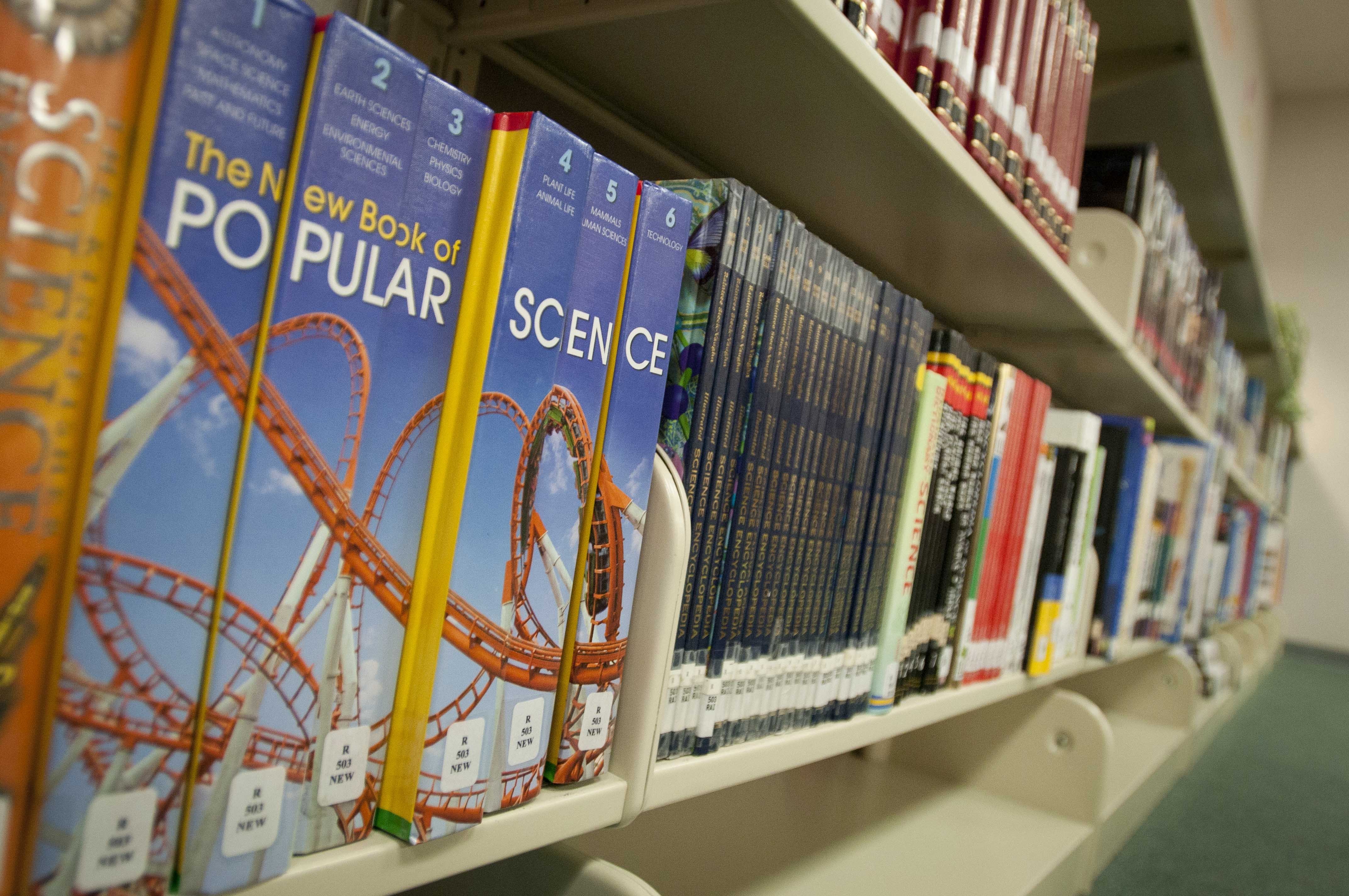 Rows of reference books on shelves inside a middle school library.