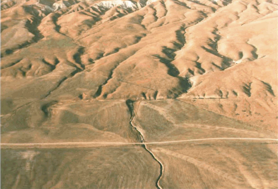 Aerial photo showing a stream channel sharply offset across a fault line in dry terrain.
