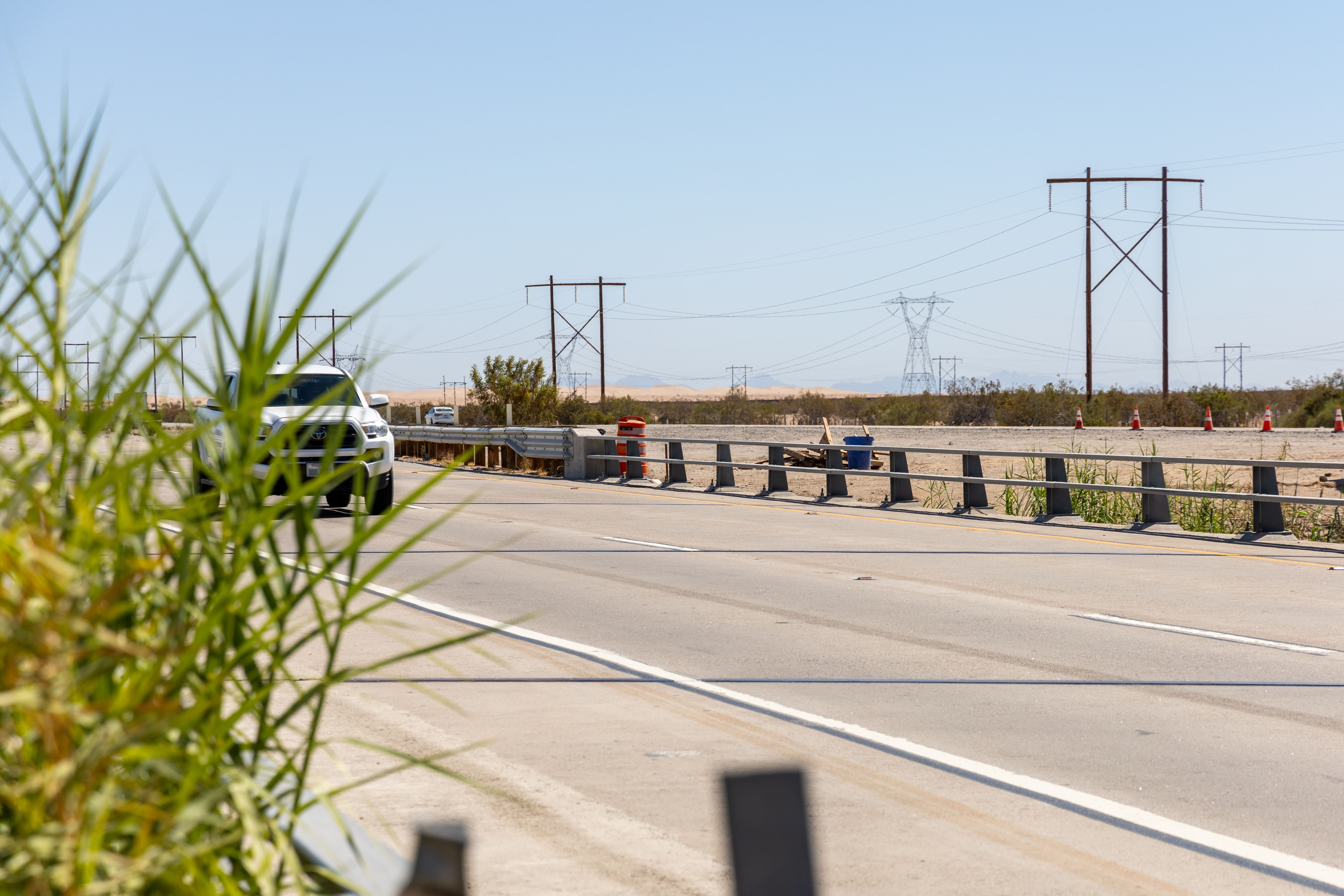 A traffic barrel on a highway shoulder housing a concealed license plate reader camera.