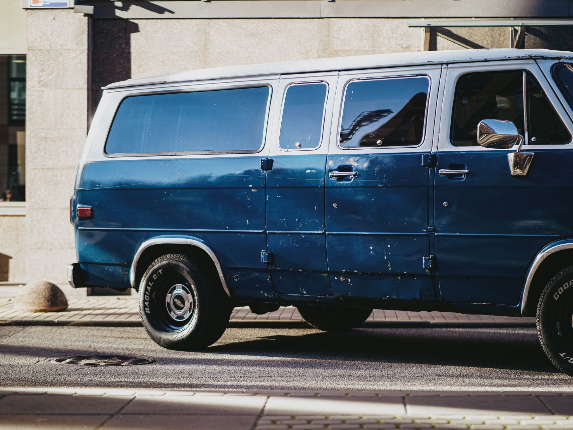 Close-up of a vintage blue van parked against a city wall, capturing urban charm.