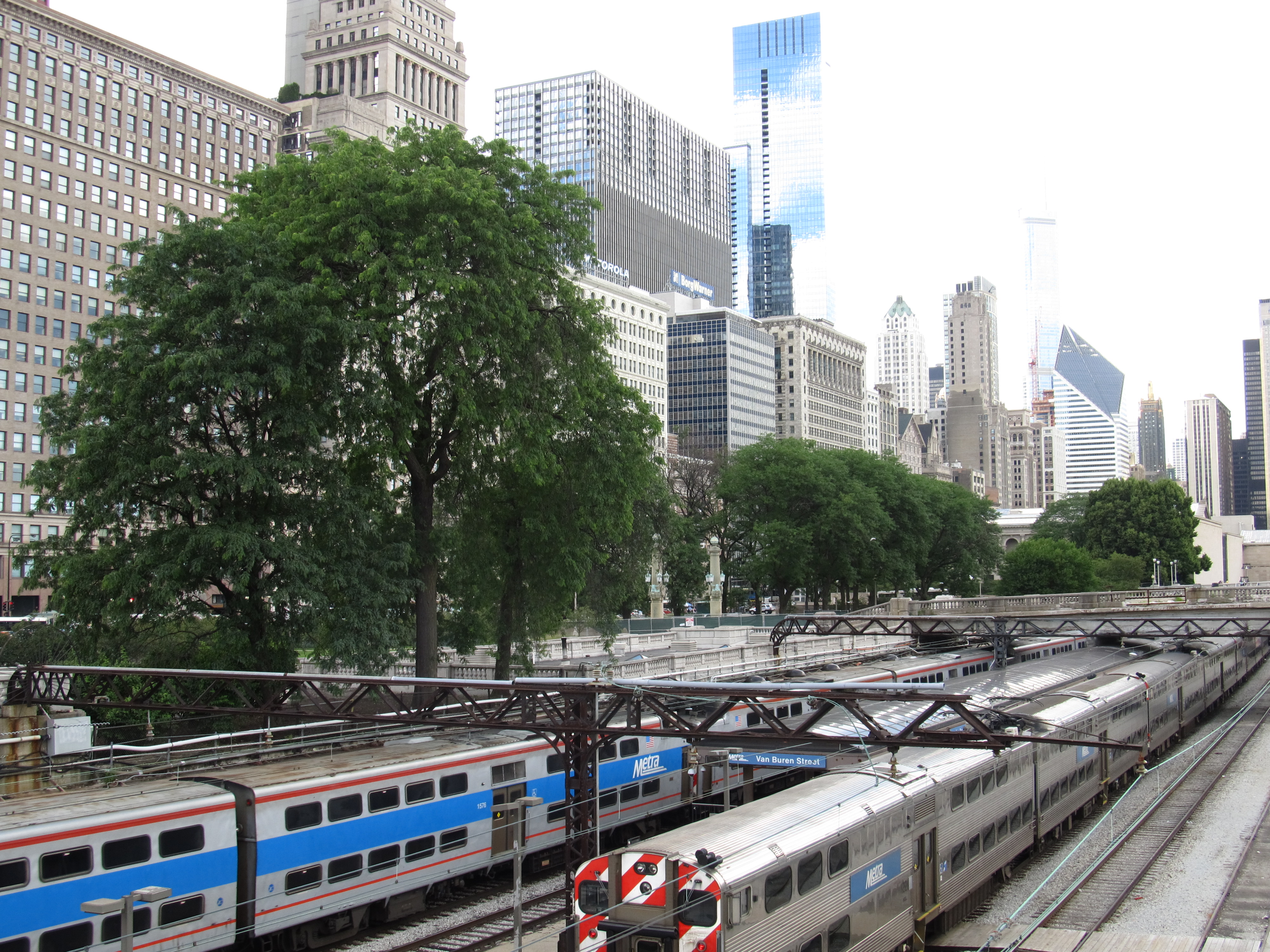 Multiple Metra commuter trains on parallel tracks with city skyscrapers in the background.