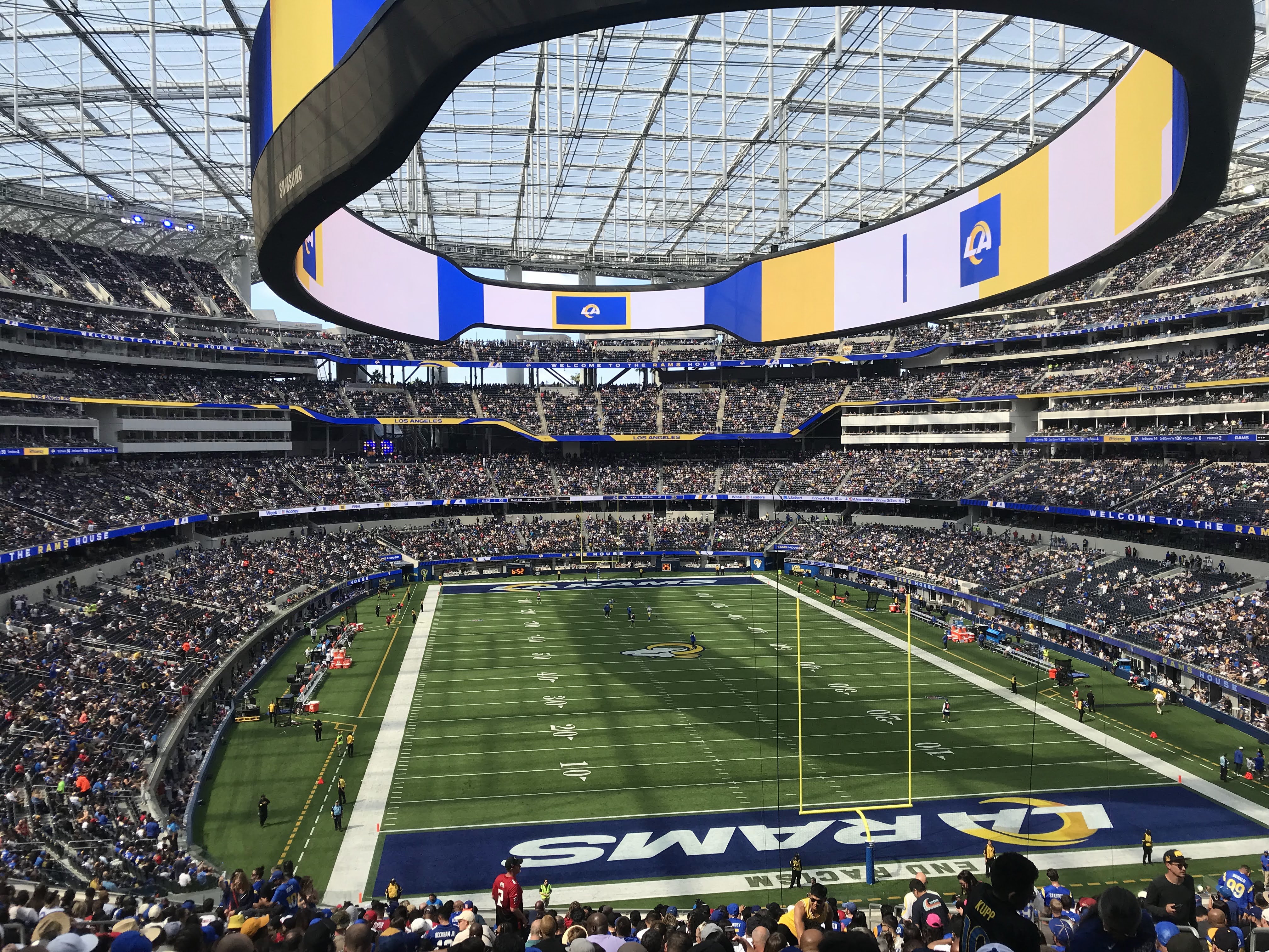 Interior of a packed NFL stadium with team branding on the circular video board and fans filling the stands.