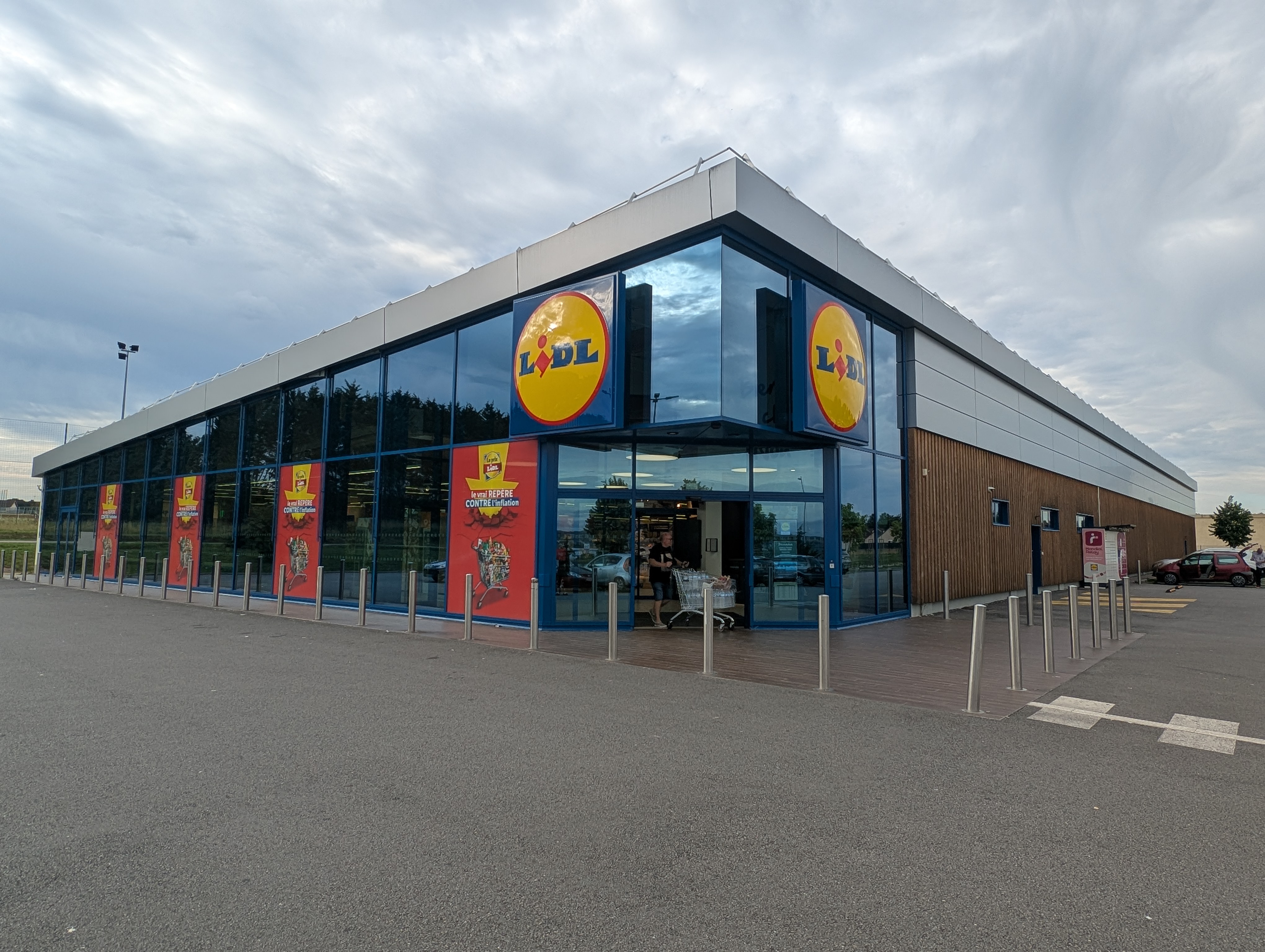 Exterior of a Lidl grocery store with large glass windows and blue framing.