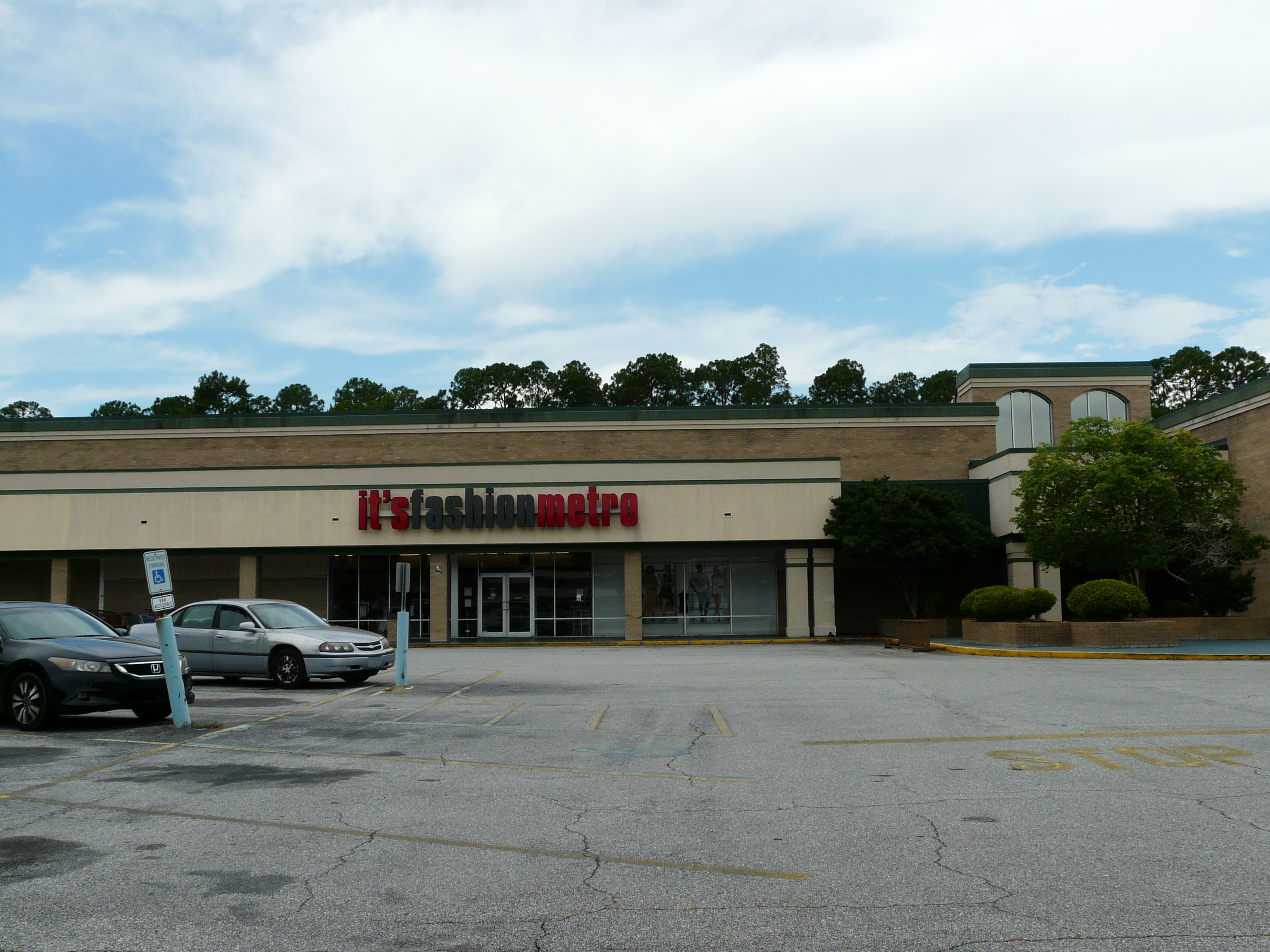 Exterior of an It's Fashion Metro store at a strip mall with a mostly empty parking lot.