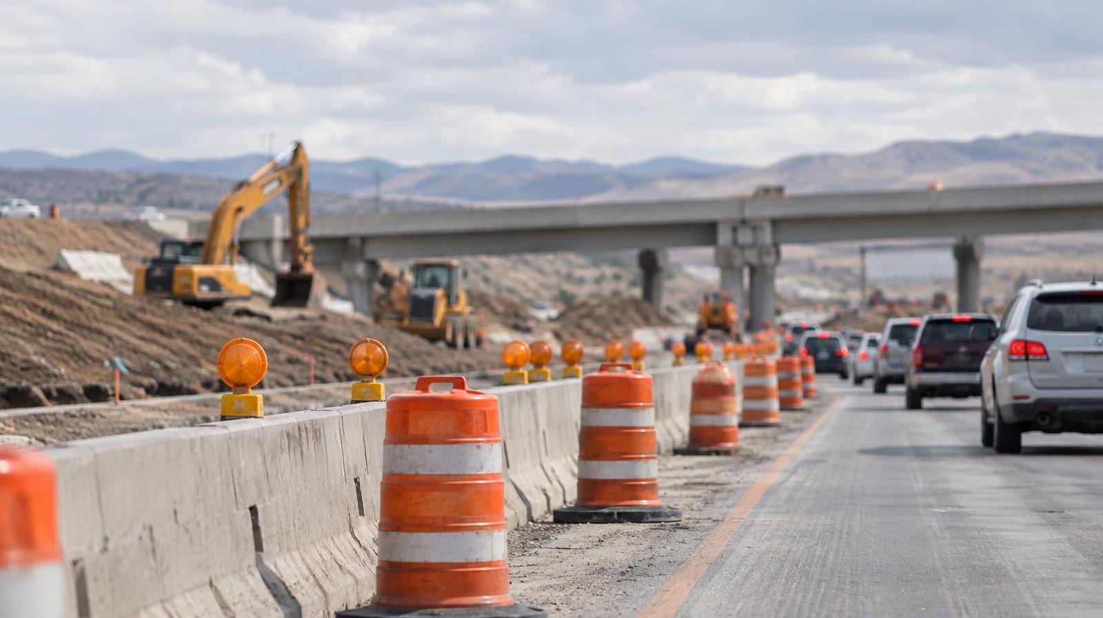 Freeway interchange under construction with orange traffic cones narrowing lanes.