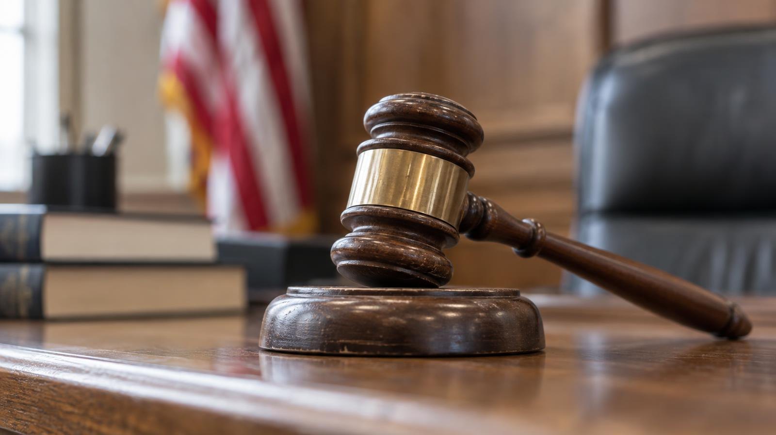 A wooden gavel resting on its sound block on a courtroom bench.