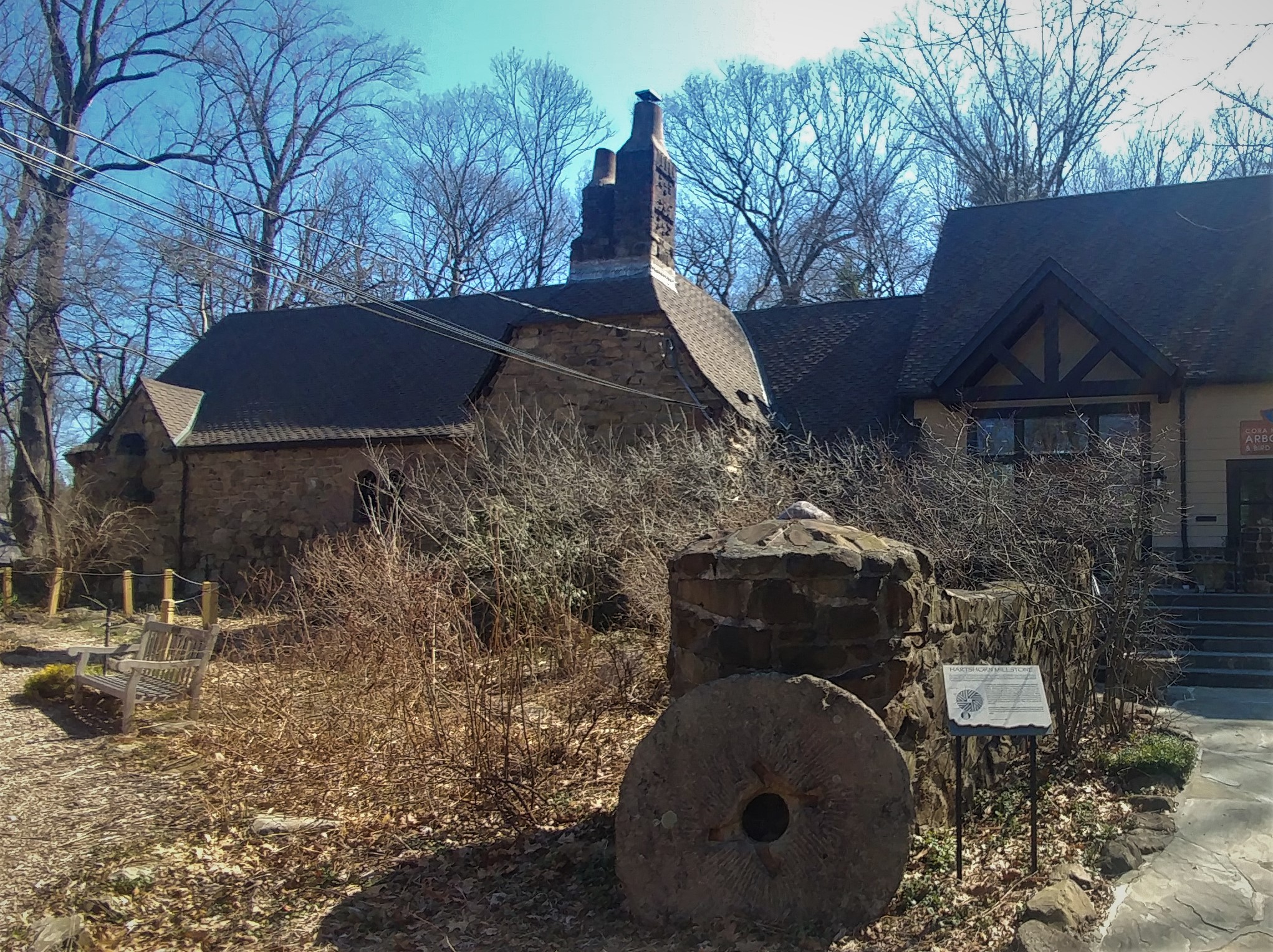 Stone building with Tudor-style architecture surrounded by trees at Cora Hartshorn Arboretum.