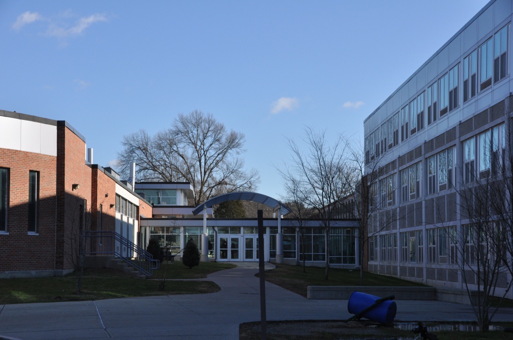 Exterior of a brick and glass school building with a blue sculpture in the foreground.
