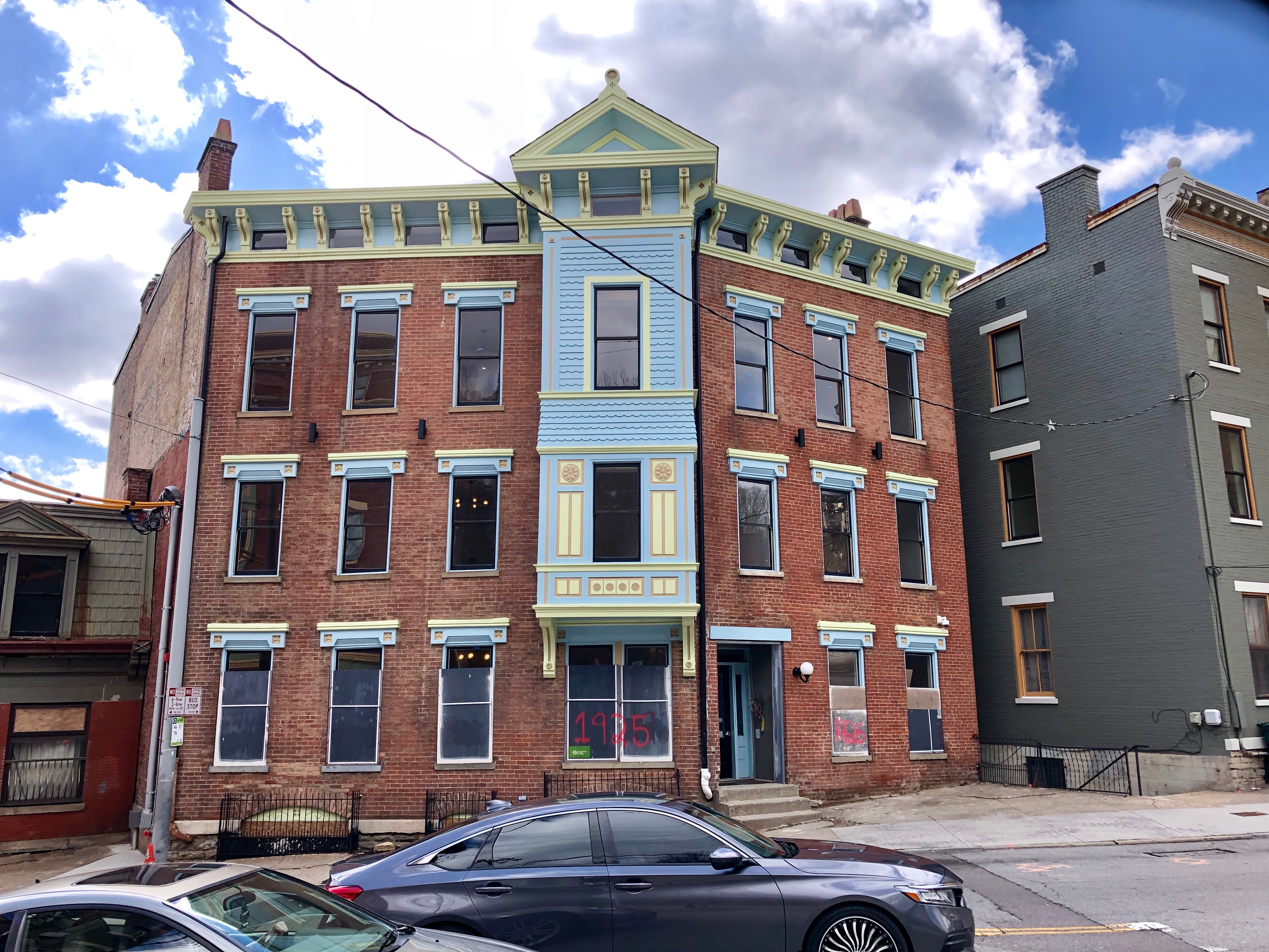 Three-story red brick building with colorful trim on Vine Street in Cincinnati.