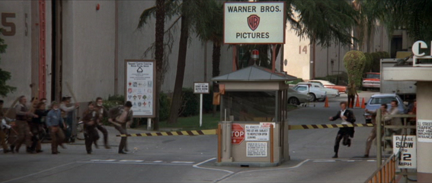 Warner Bros. Studios entrance gate with shield logo, guard booth, and studio buildings in Burbank.