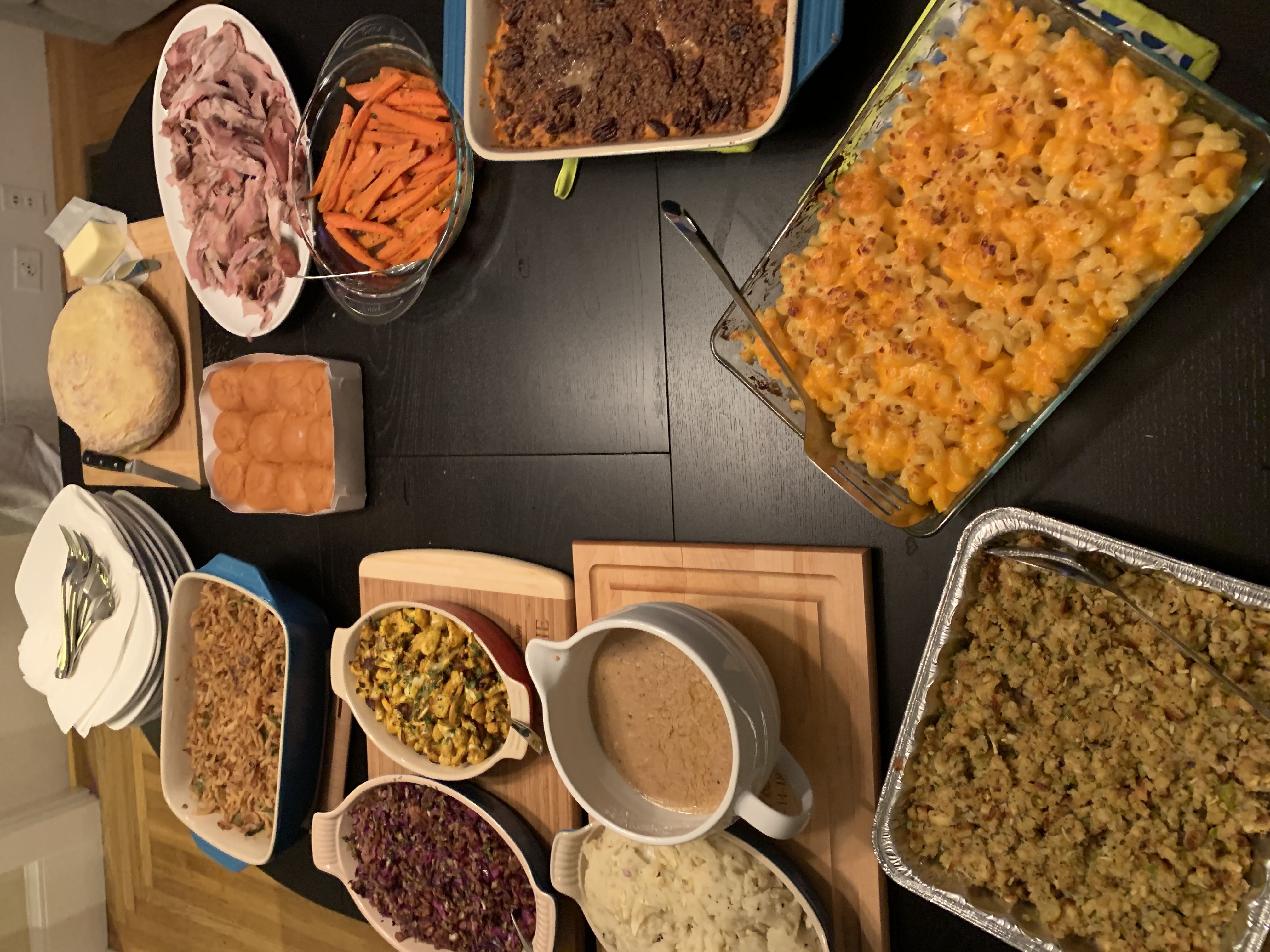 A table spread with Thanksgiving dishes including turkey, stuffing, mashed potatoes, and rolls.