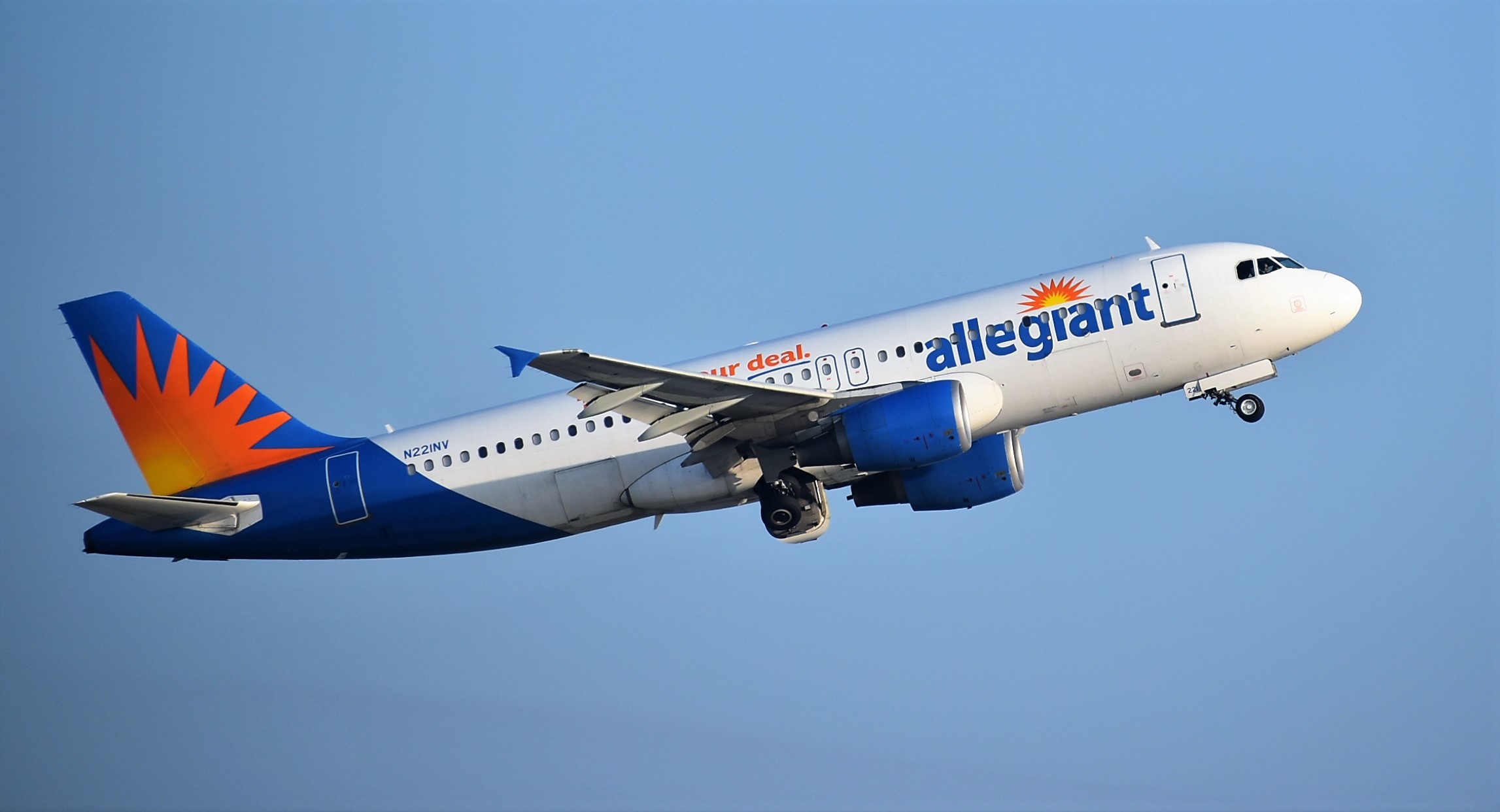 An Allegiant Air jet climbs after takeoff with landing gear retracting against a blue sky.