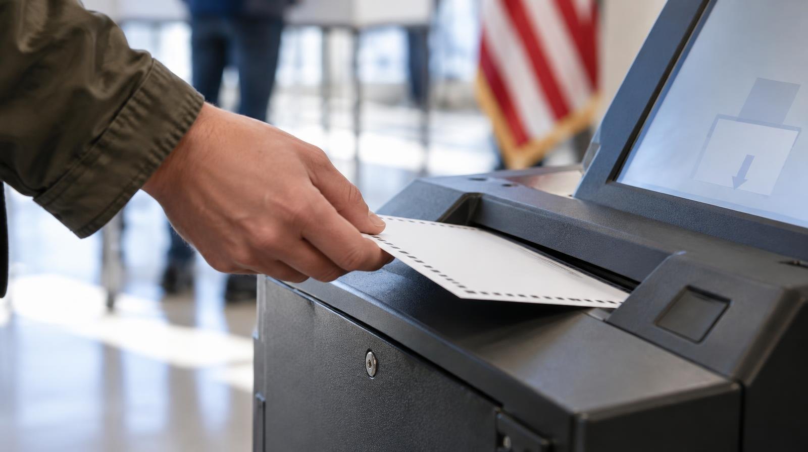 A ballot being inserted into a voting tabulator machine.