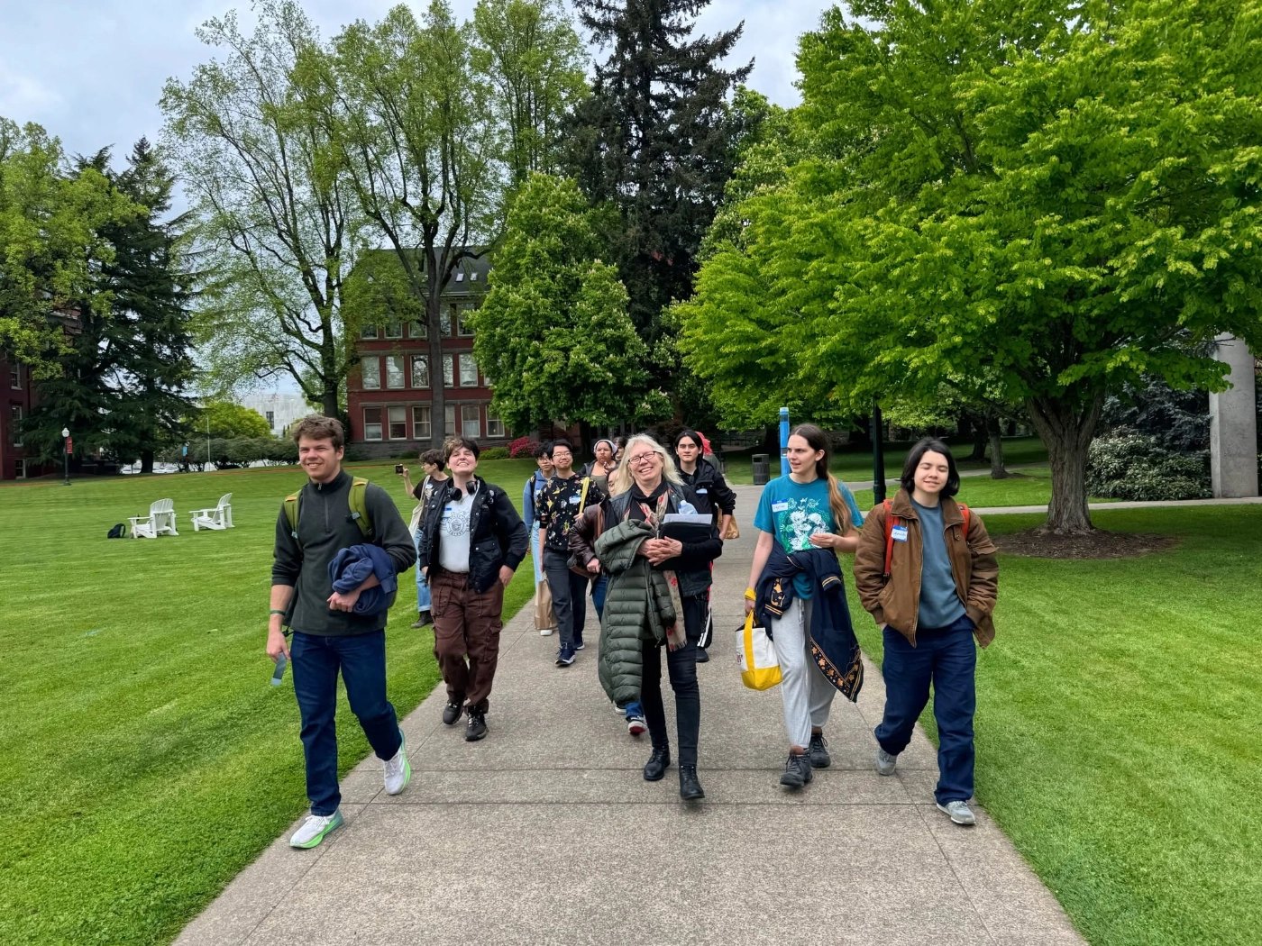 Group of students walking together on a tree-lined university campus path.