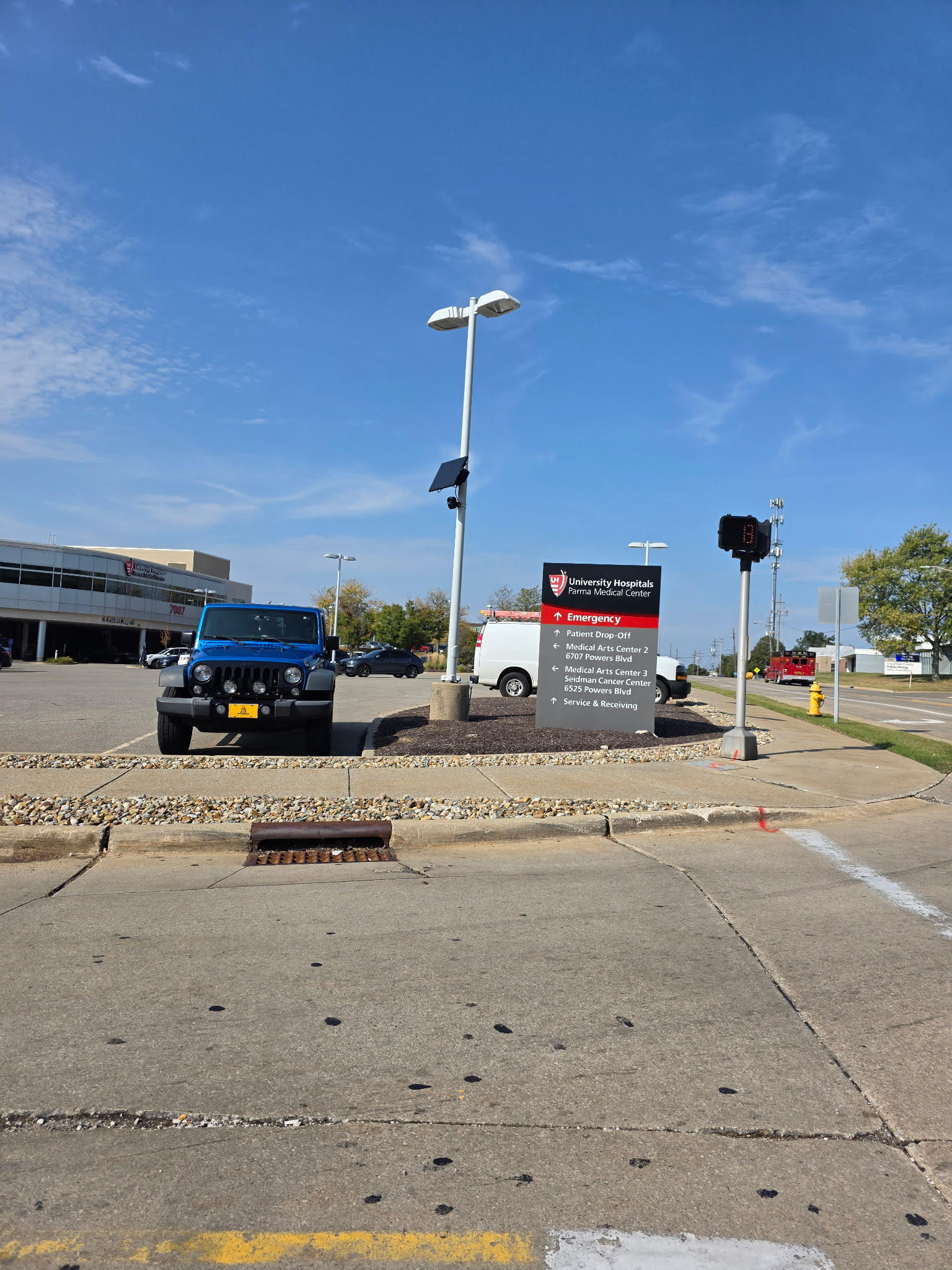 Black license plate reader camera on a white pole at a parking lot entrance in Ohio.
