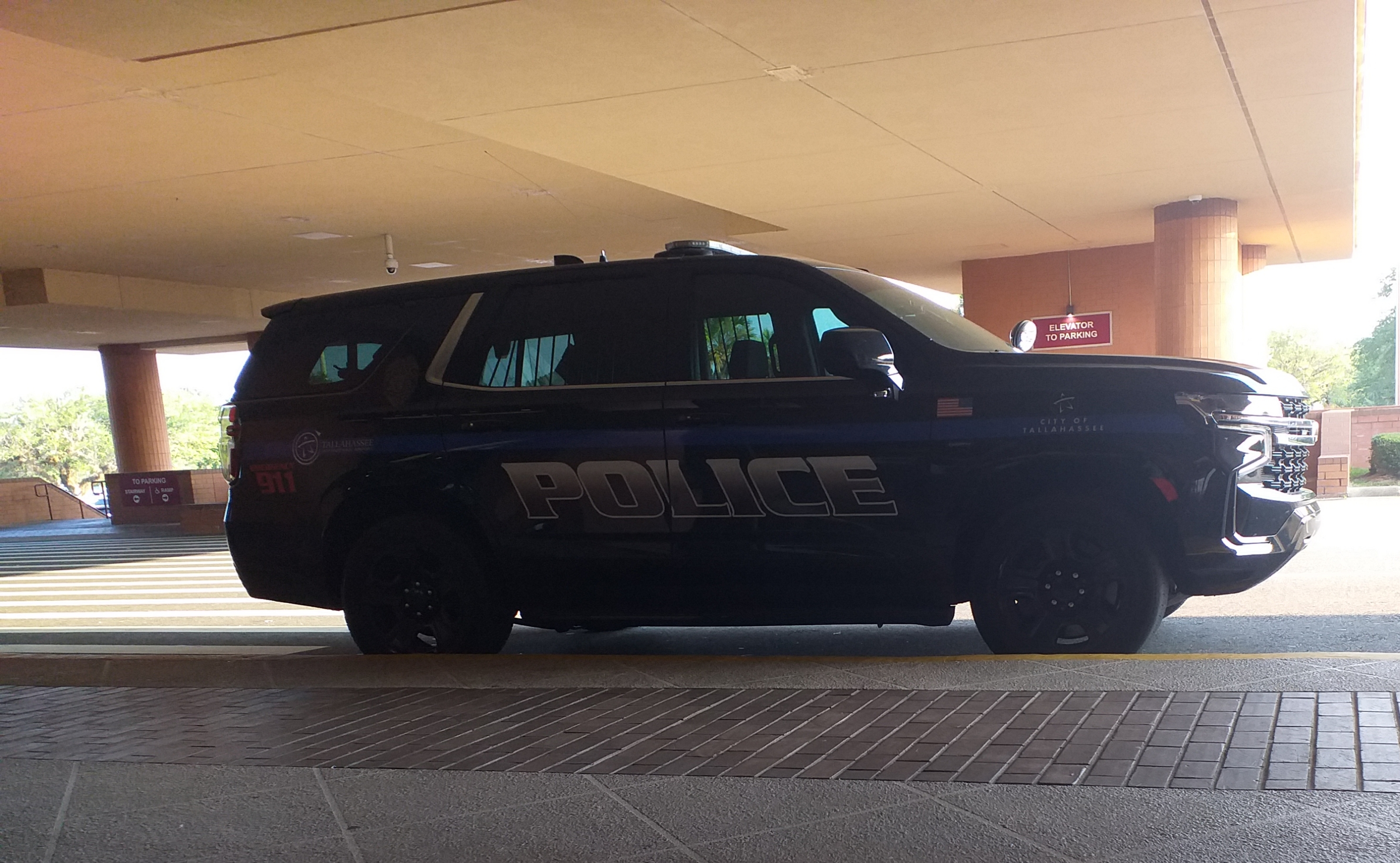 A black police SUV with POLICE markings parked under a covered structure.