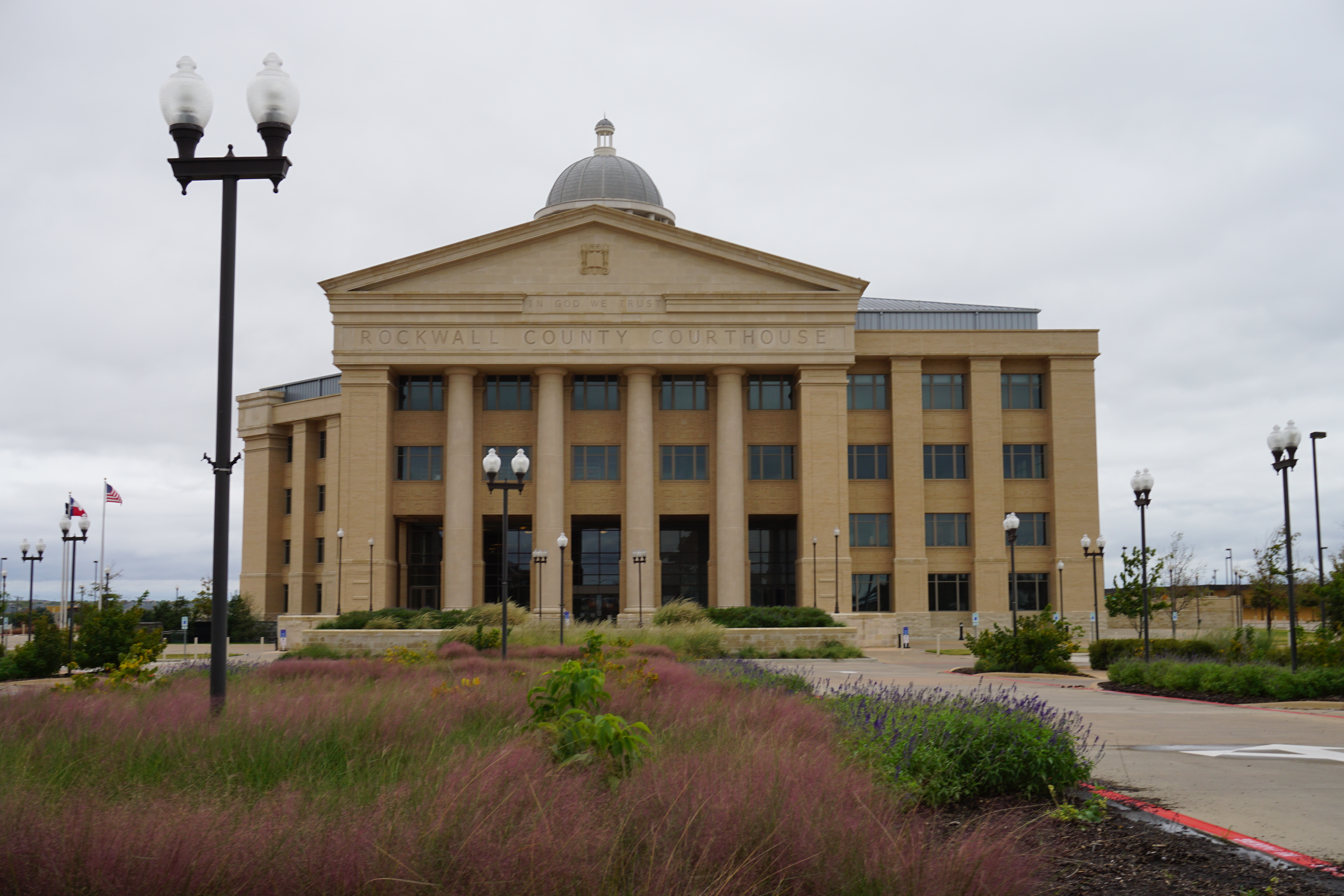 Neoclassical courthouse with dome and columns surrounded by ornamental grasses.