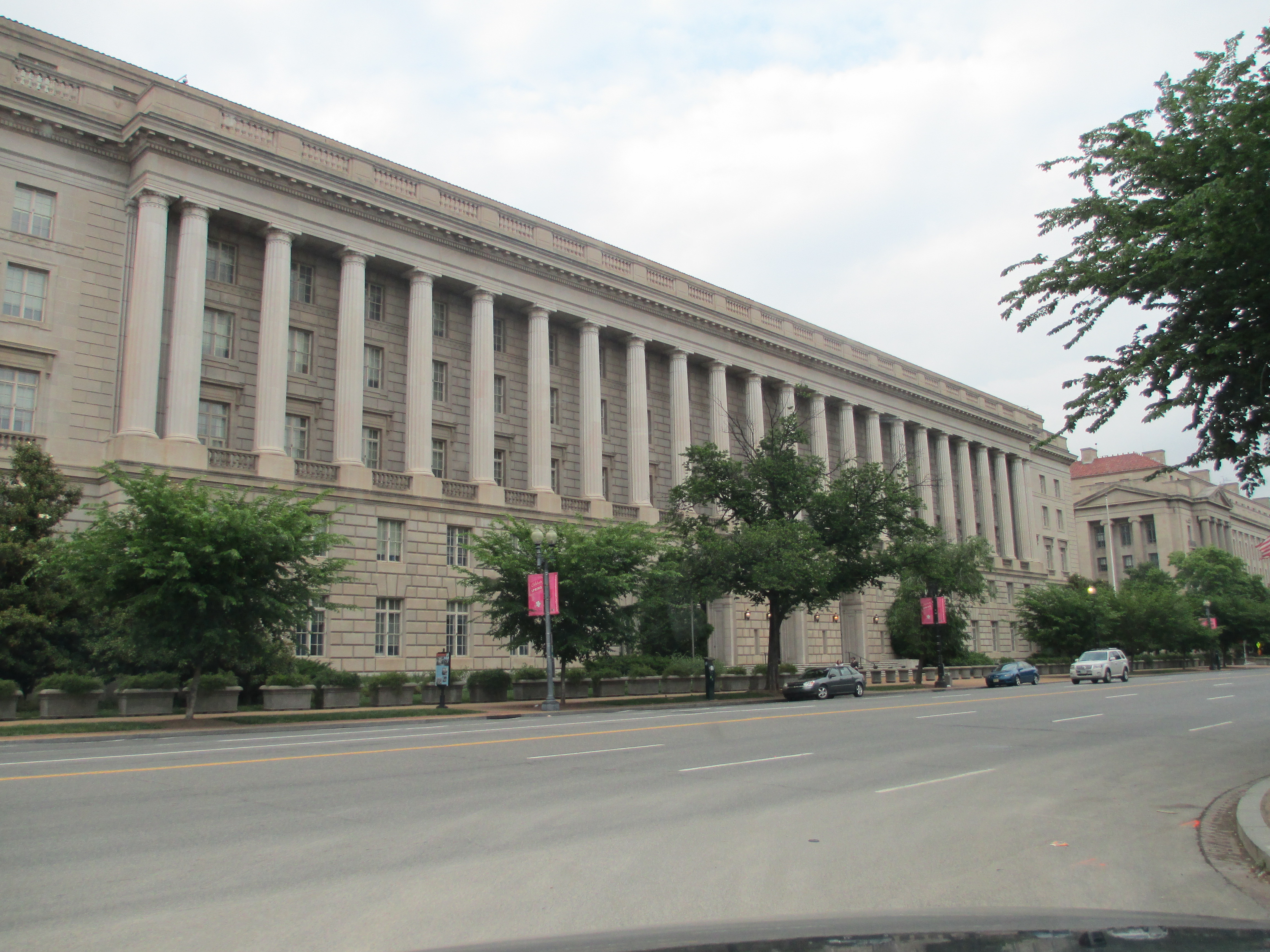 Large neoclassical government building with columns and red banners lining the facade.