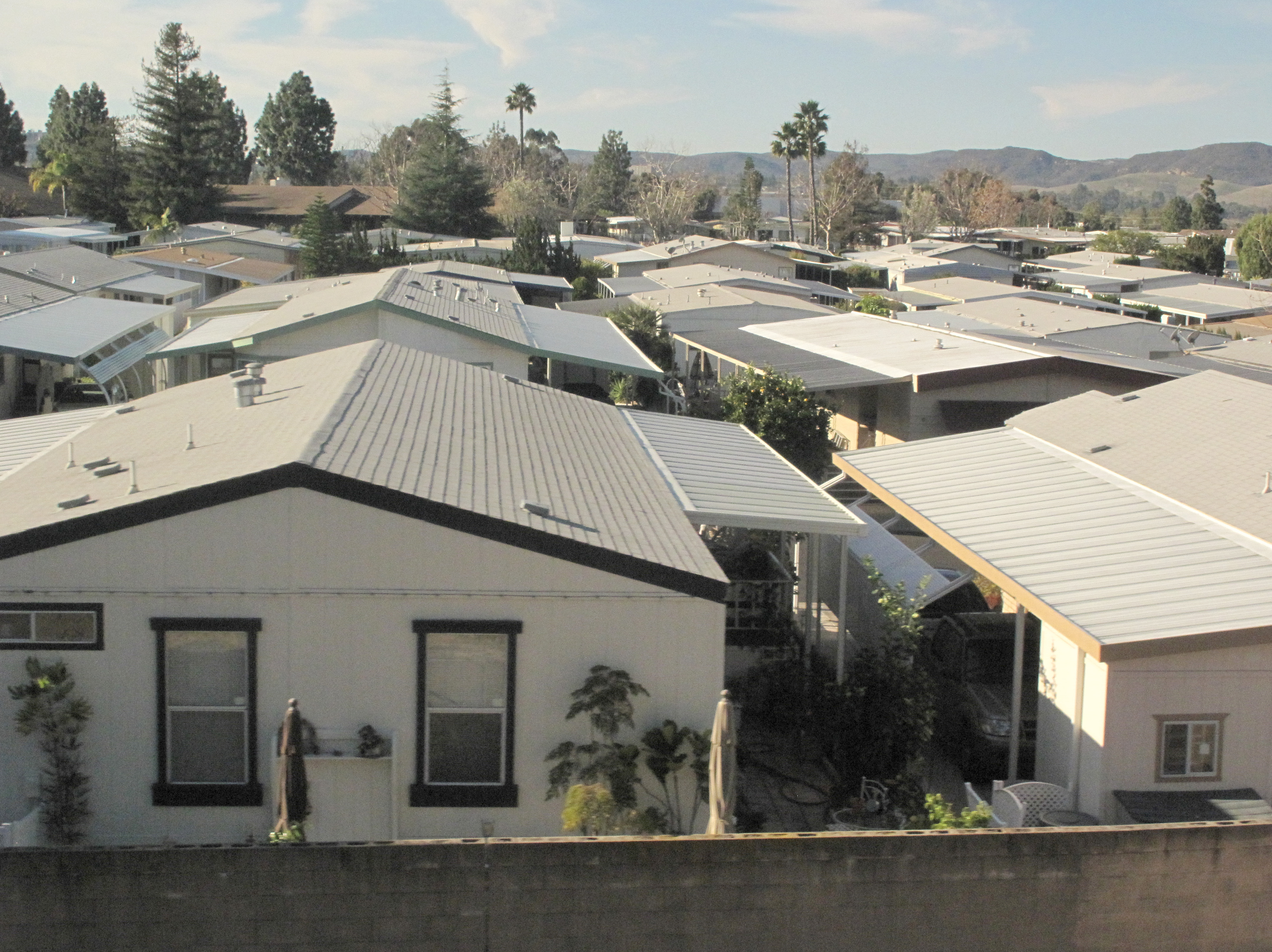 Aerial view of rows of manufactured homes with metal roofs packed closely together.