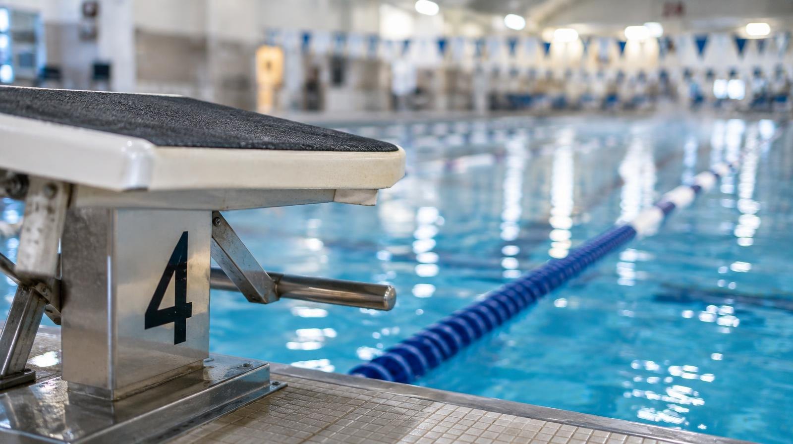 A starting block at the edge of an indoor swimming pool with lane dividers.
