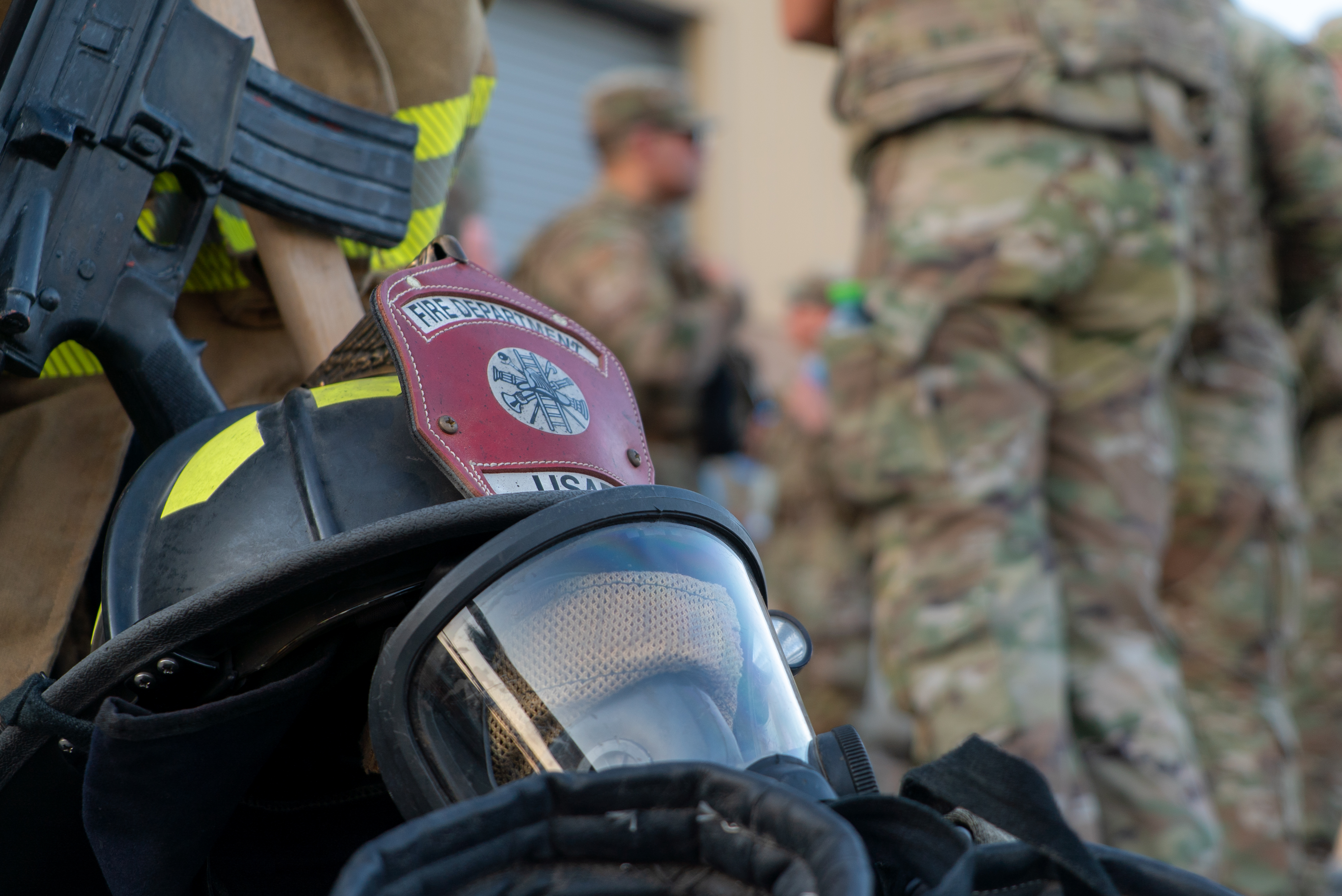 Firefighter helmet, turnout gear, and a rifle arranged as a ceremonial 9/11 tribute display.