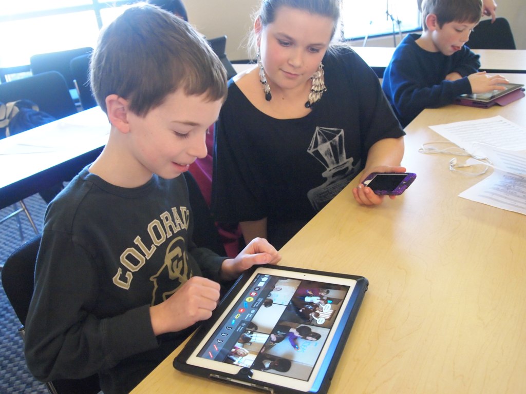 Two young students share an iPad at a classroom desk.