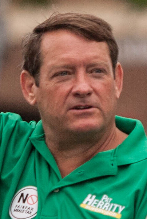 Man in a green polo shirt with a name logo, photographed outdoors.