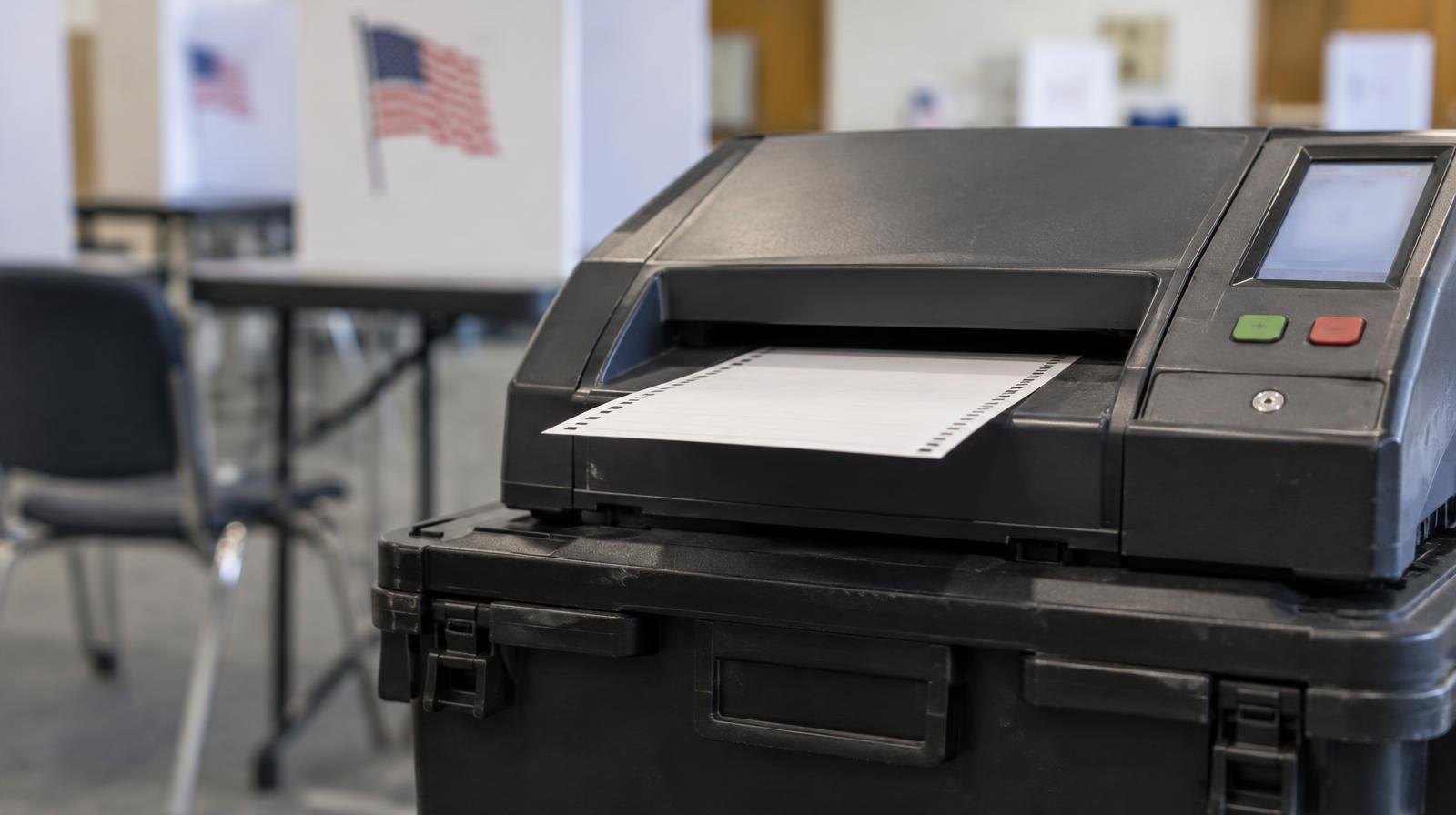 An optical-scan ballot tabulator machine sitting on a collapsible ballot box.
