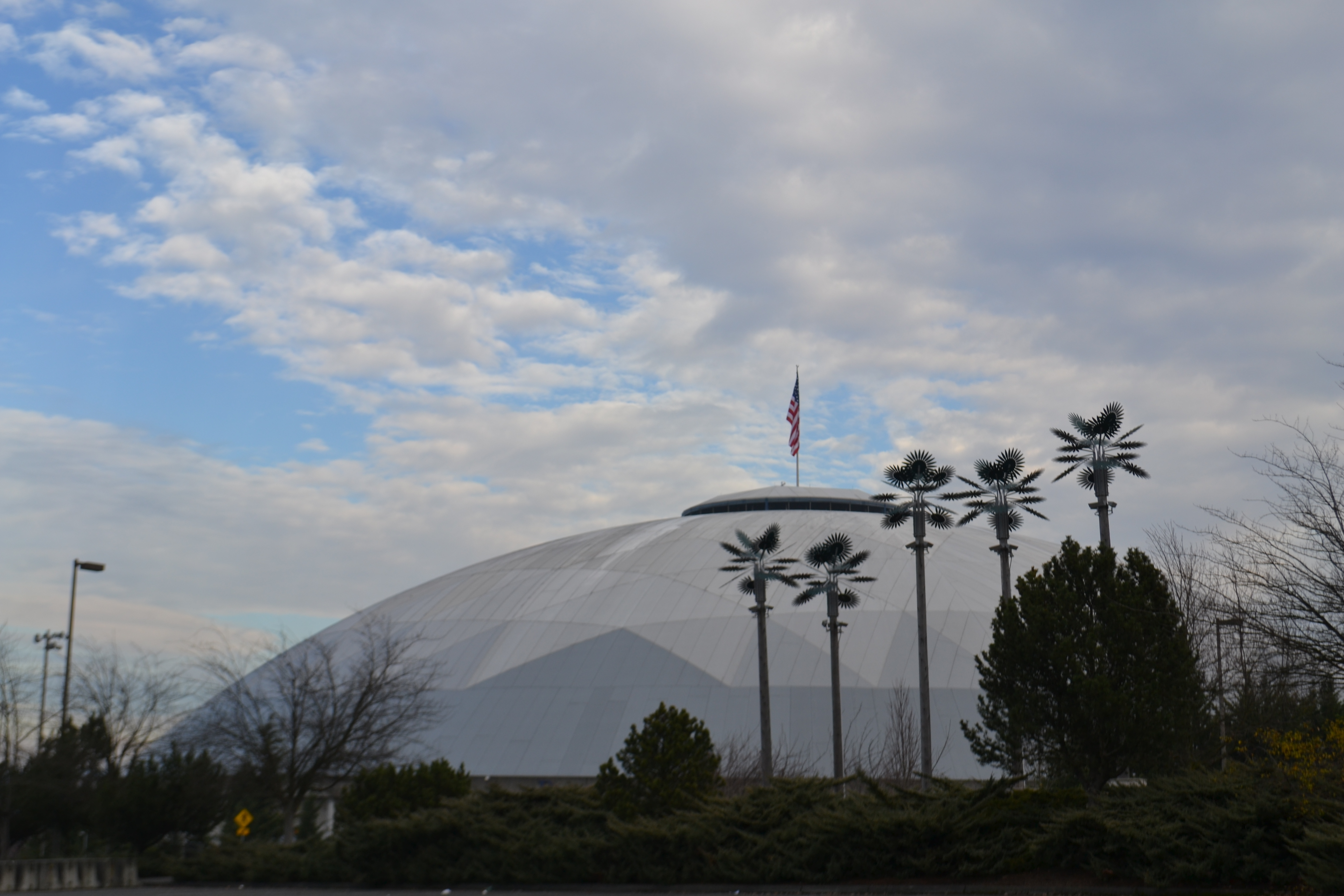 Large silver dome arena exterior with decorative metal palm tree sculptures in the foreground.