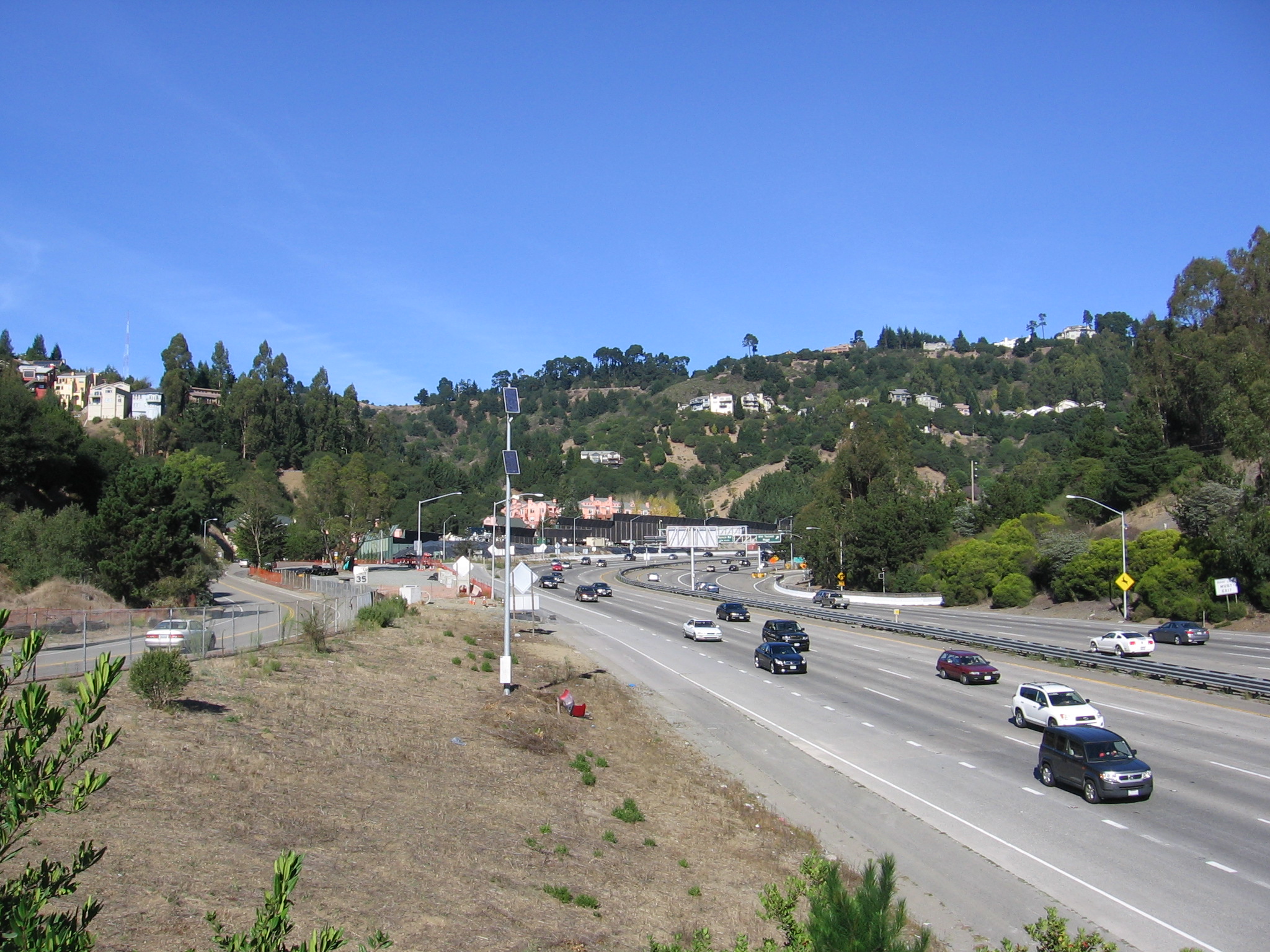 Multi-lane freeway with traffic approaching the Caldecott Tunnel portals in the hills.